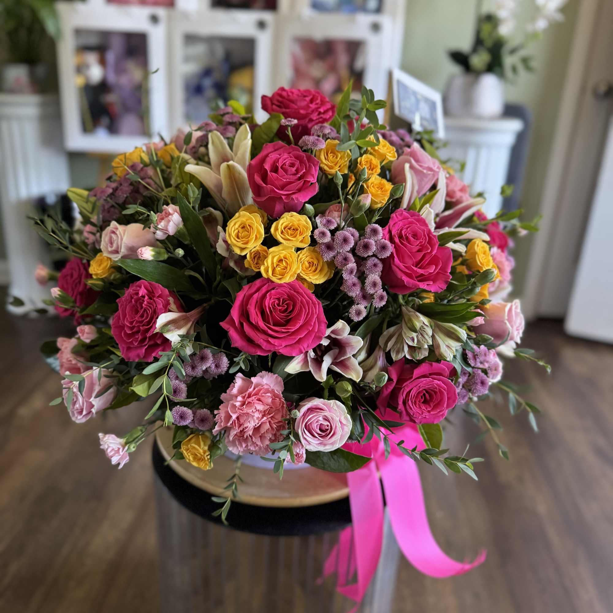 Large bouquet of pink, yellow, and white flowers with a pink ribbon