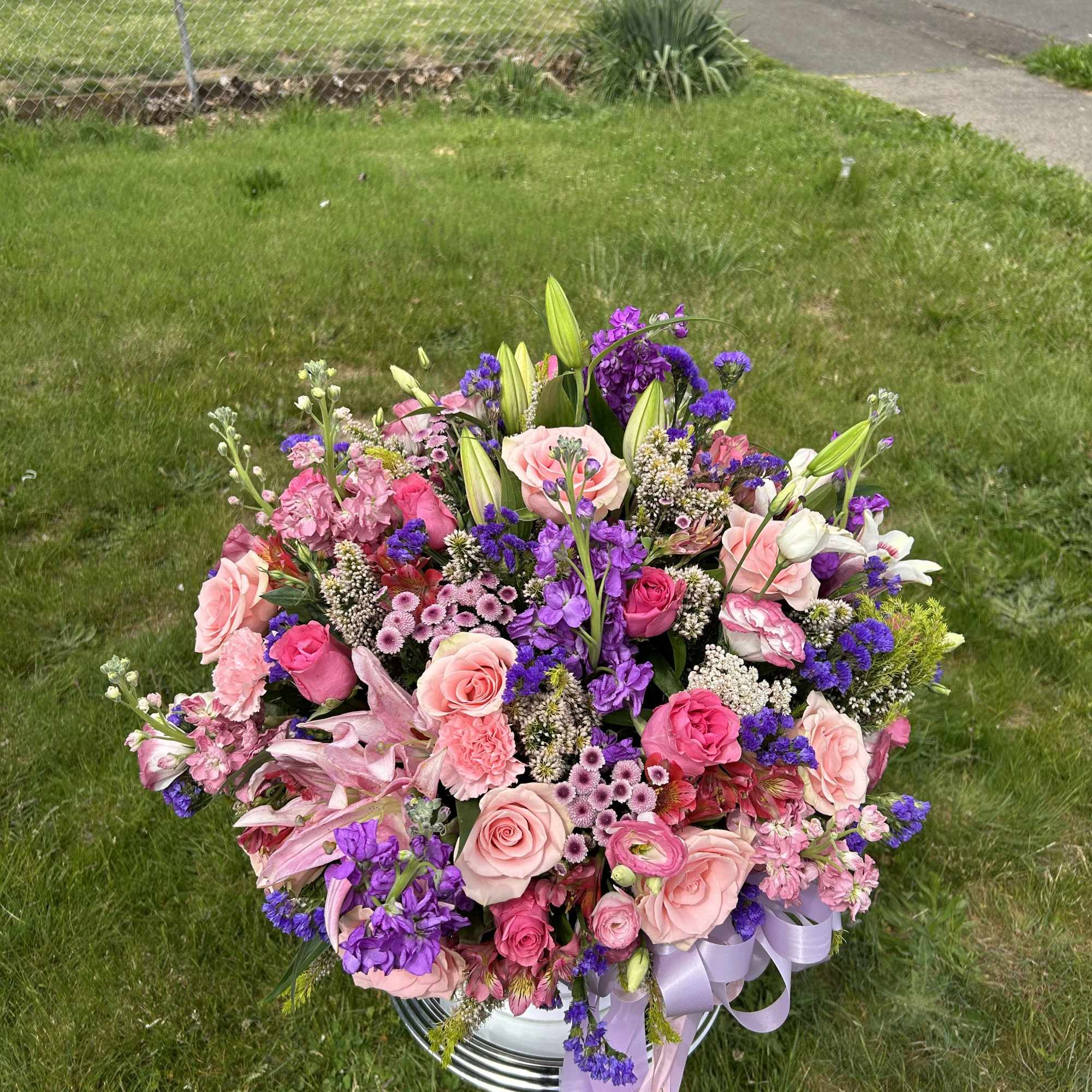 Large pink and purple flower arrangement in a silver pedestal vase