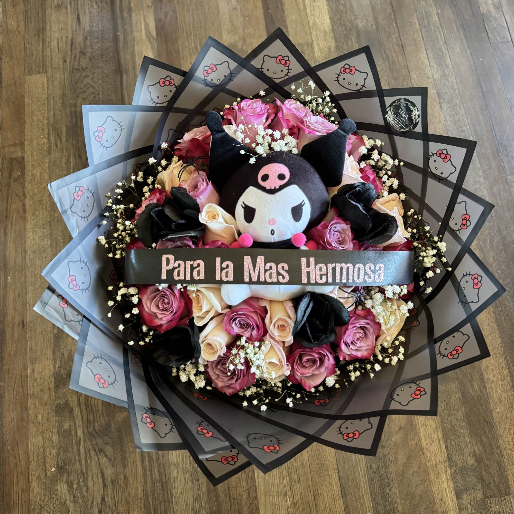 Round bouquet of pink and cream roses with a plush character in the center