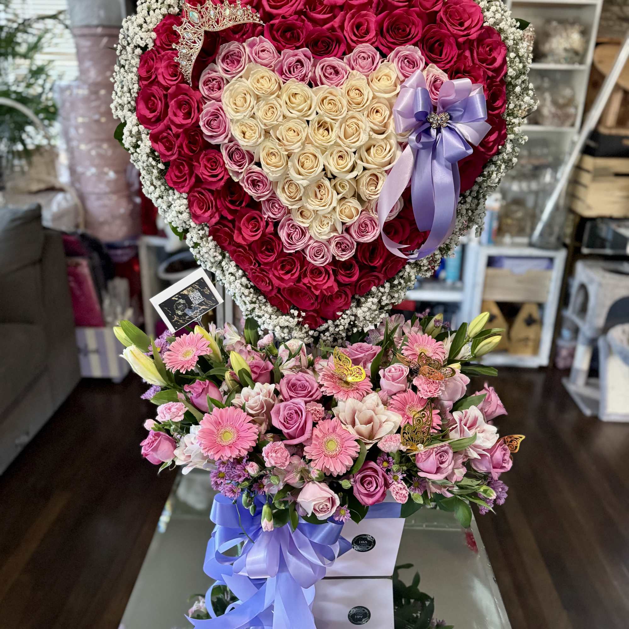 Heart-shaped rose arrangement with a purple ribbon and crown topper
