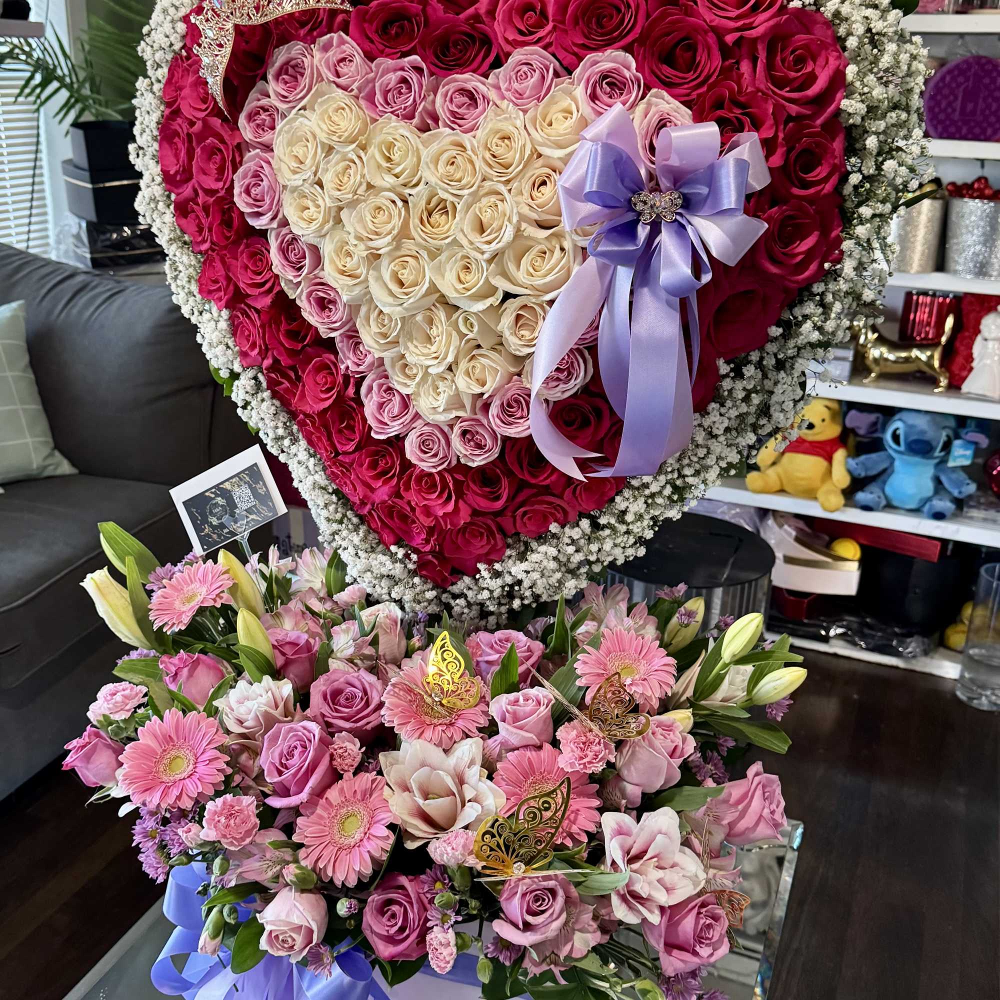 Heart-shaped rose arrangement with a lavender bow and a mixed pink bouquet below