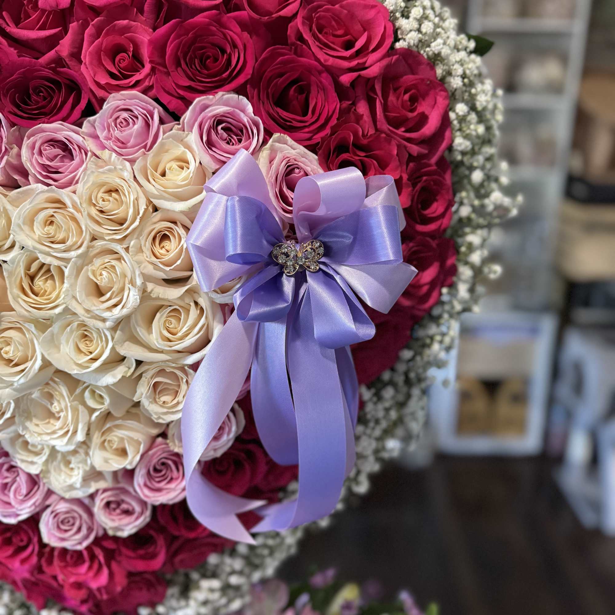 Heart-shaped rose arrangement with a lavender ribbon bow