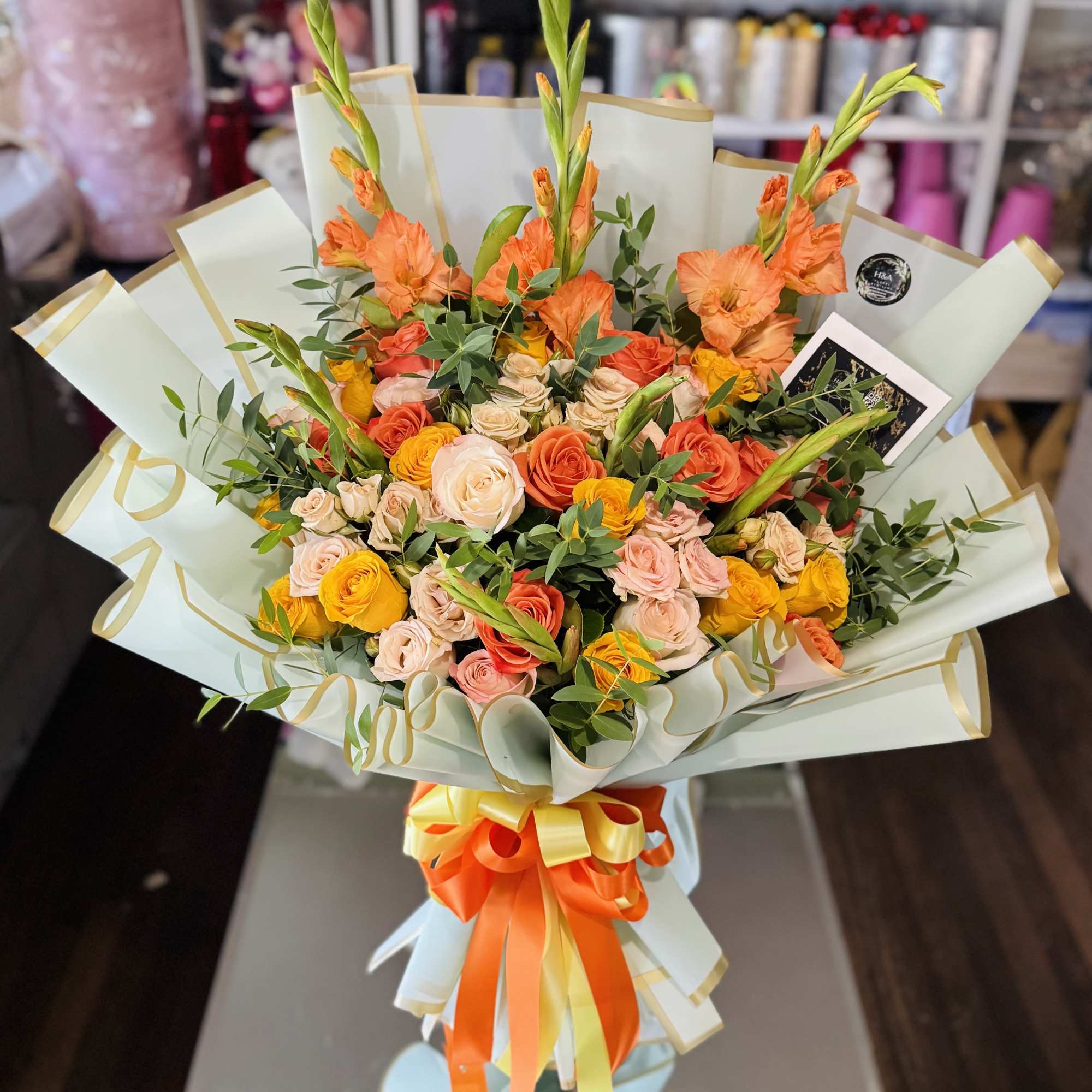 Large bouquet of orange, yellow, and blush roses with tall orange blooms