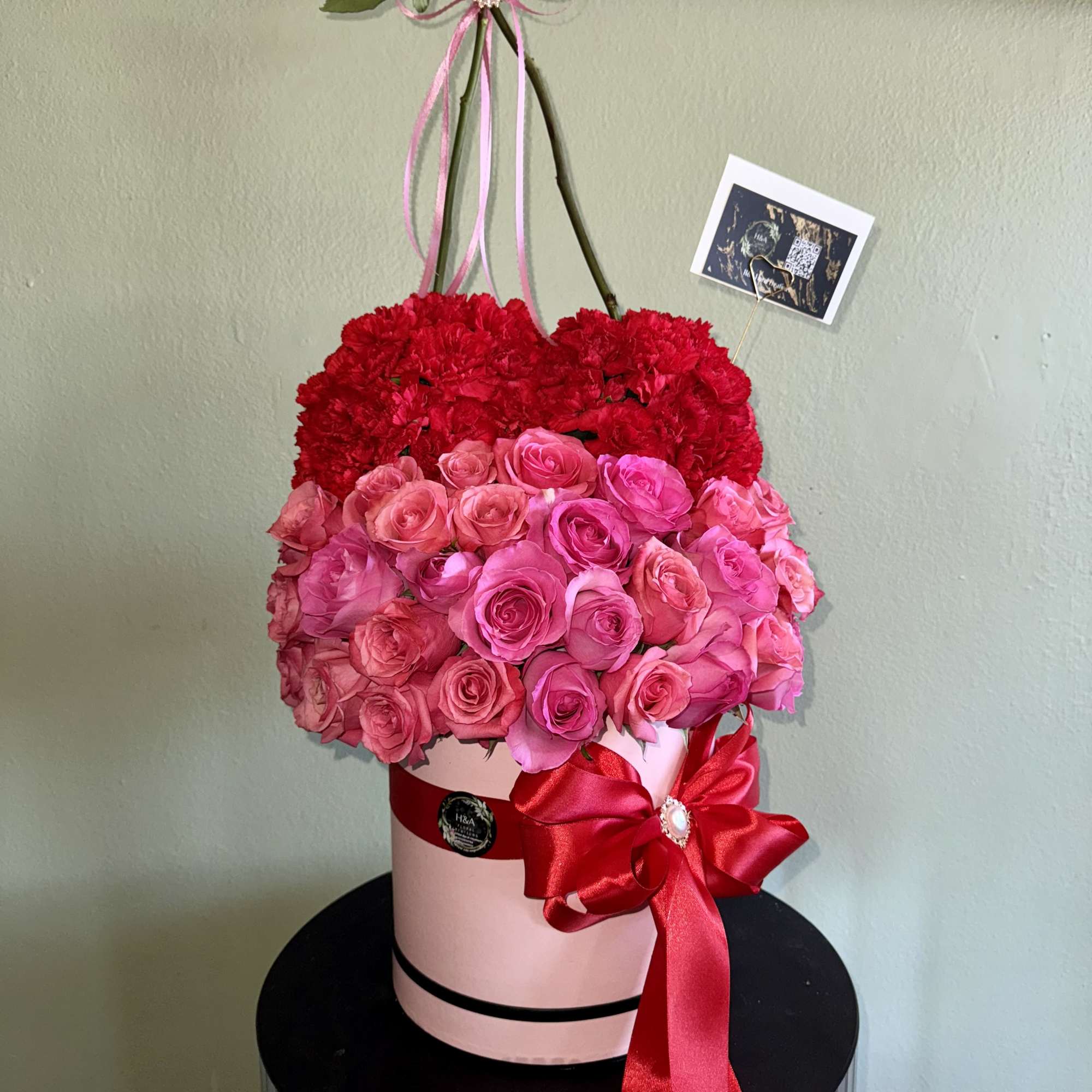 Heart-shaped floral arrangement of red carnations and pink roses in a pink box, photo 2 of 2