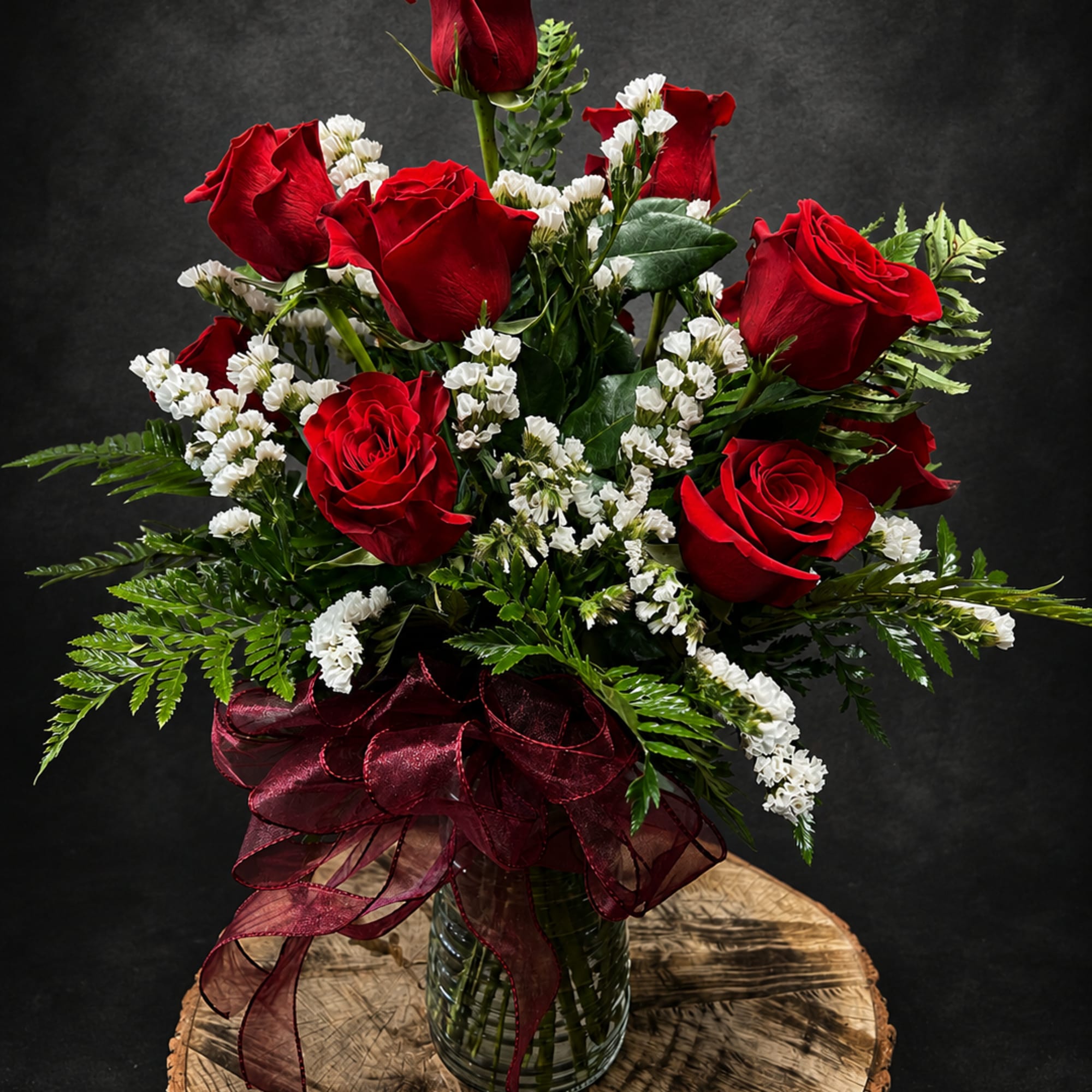 Deep red roses clustered with delicate white stock create a timeless dozen-rose