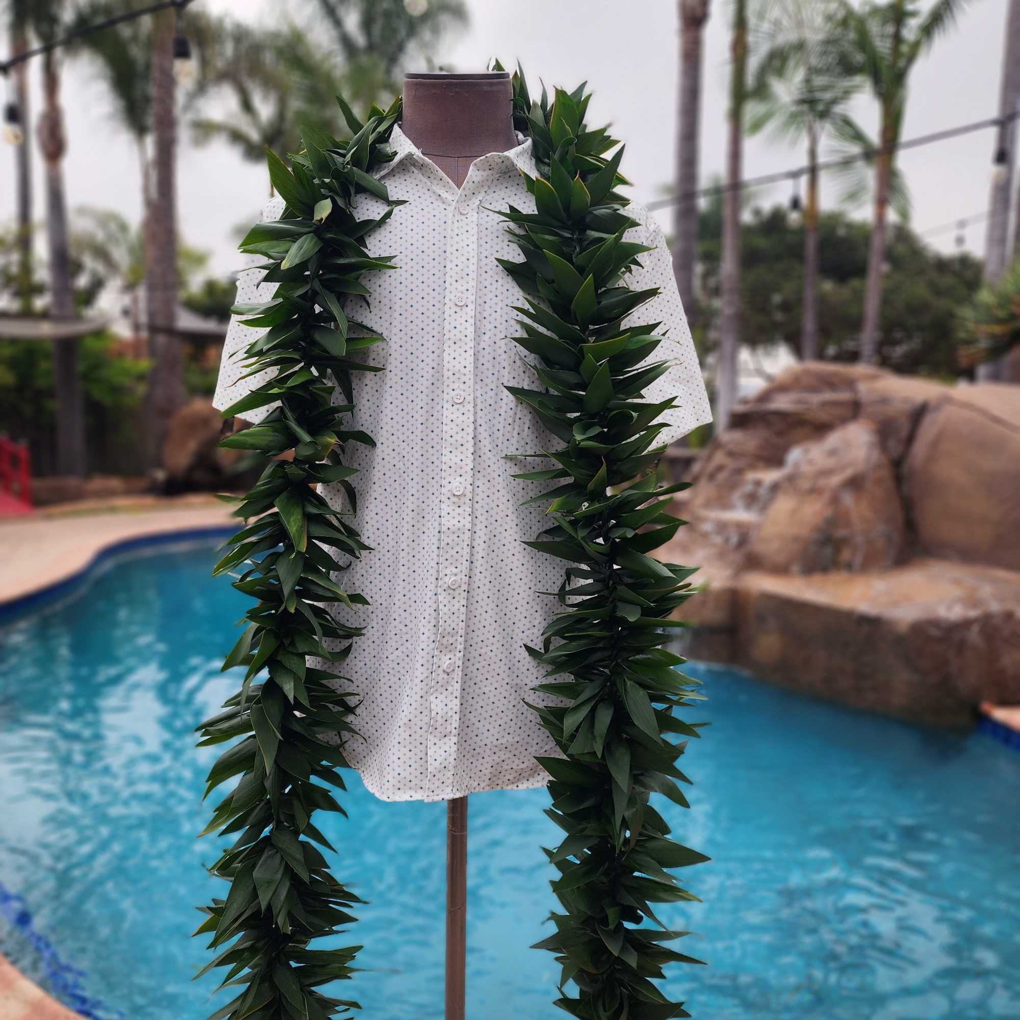 White shirt on a mannequin with two long green leaf leis