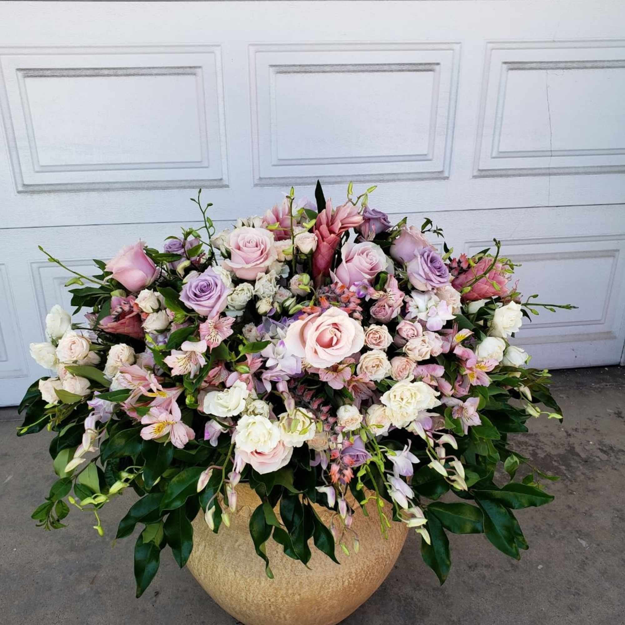 Large pastel floral arrangement in a round gold vase