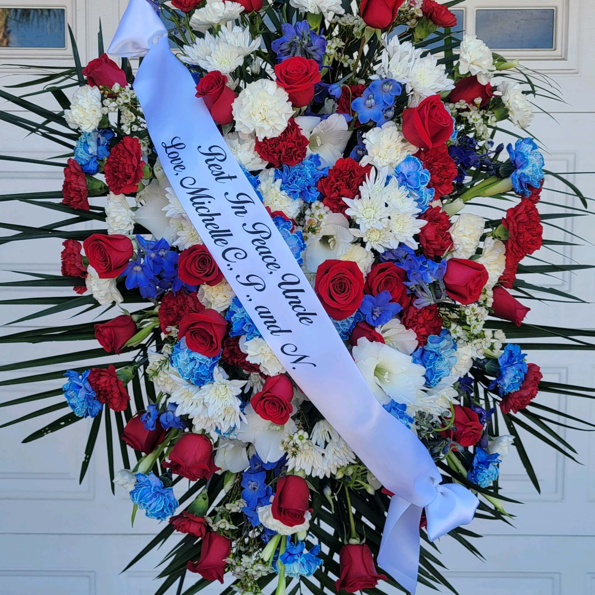 Large red, white, and blue funeral wreath with a memorial ribbon