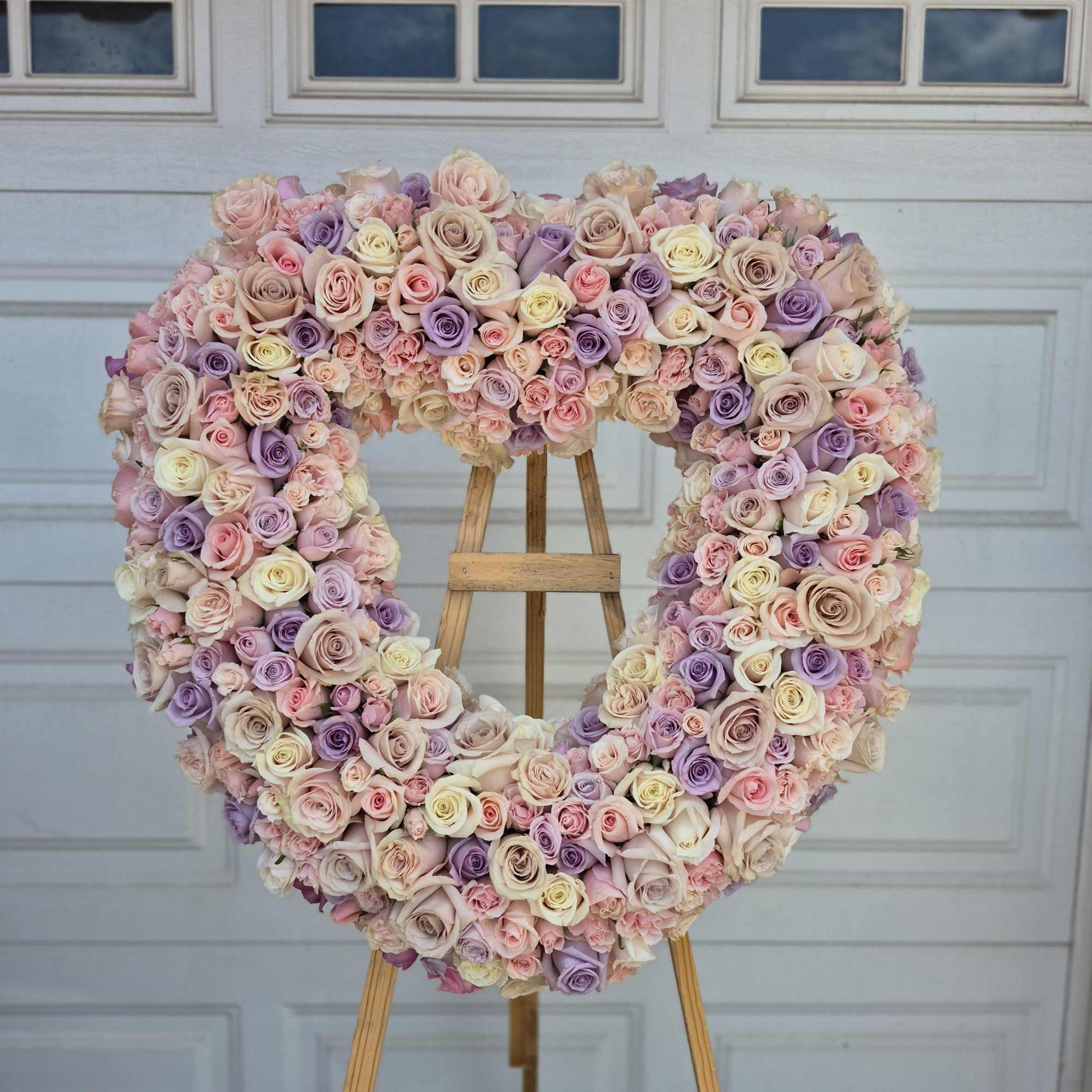Heart-shaped rose arrangement on an easel in pastel pink, lavender, and cream