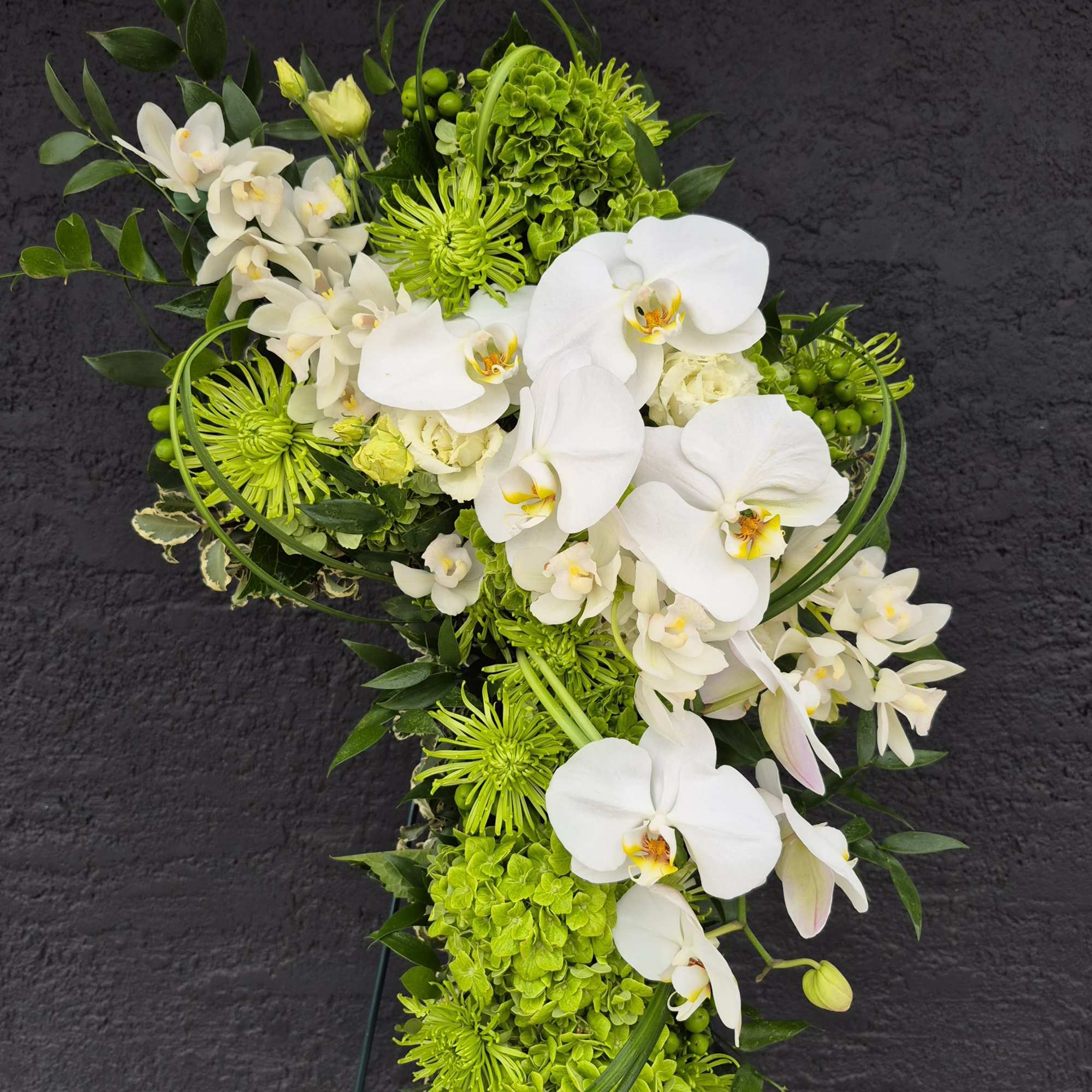 White orchids and green flowers arranged in a tall standing spray