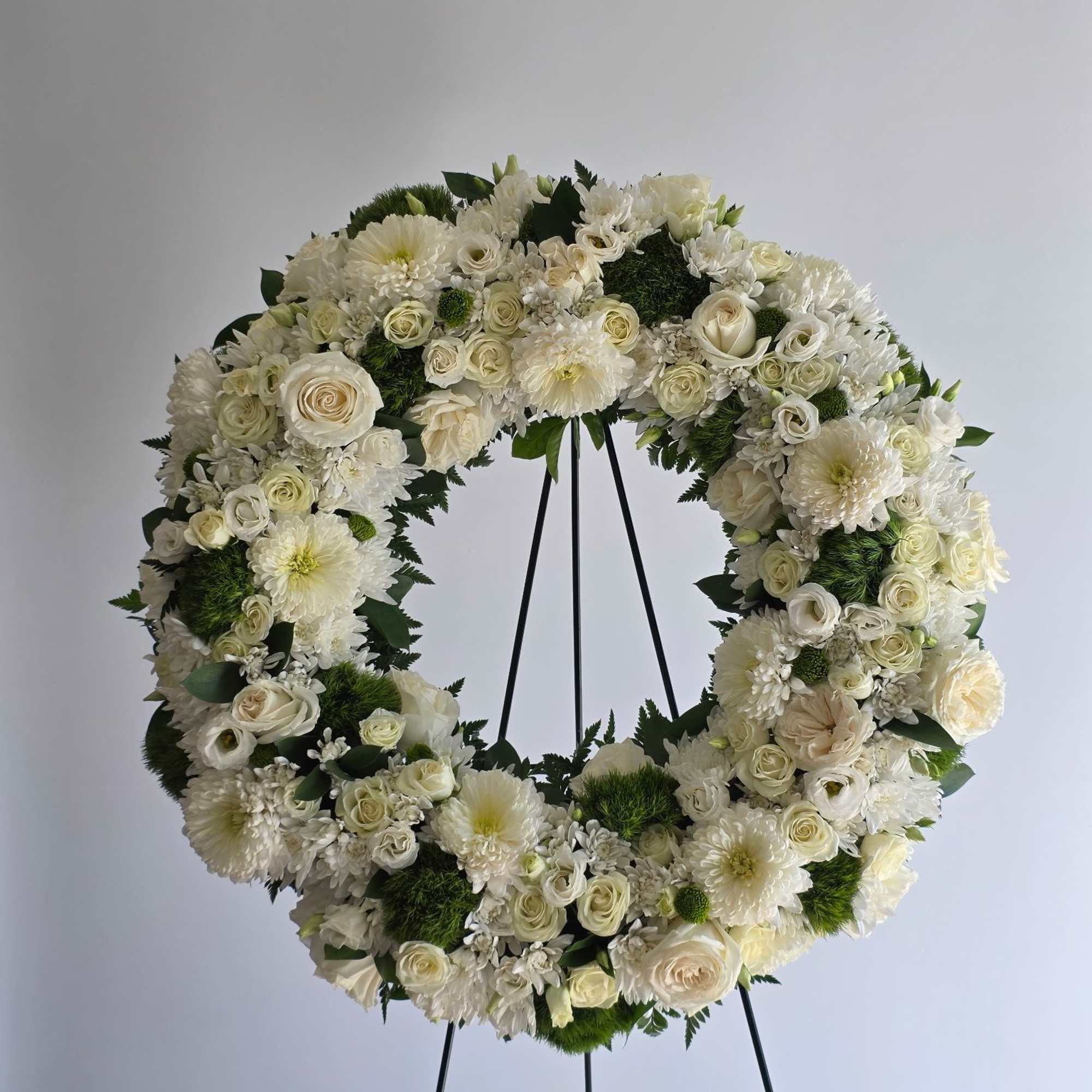 White floral wreath on a black stand