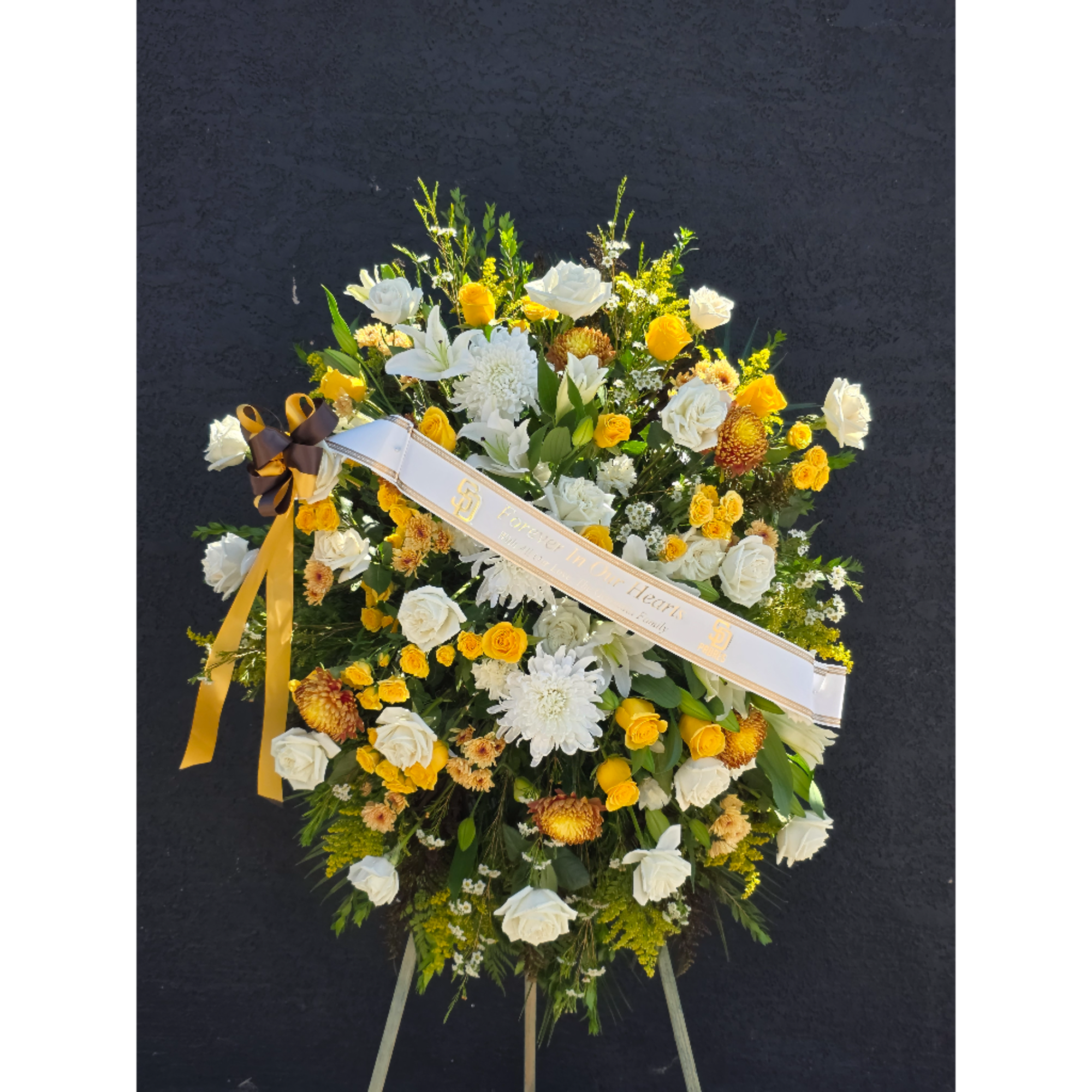 Large white and yellow floral standing spray with a ribbon sash