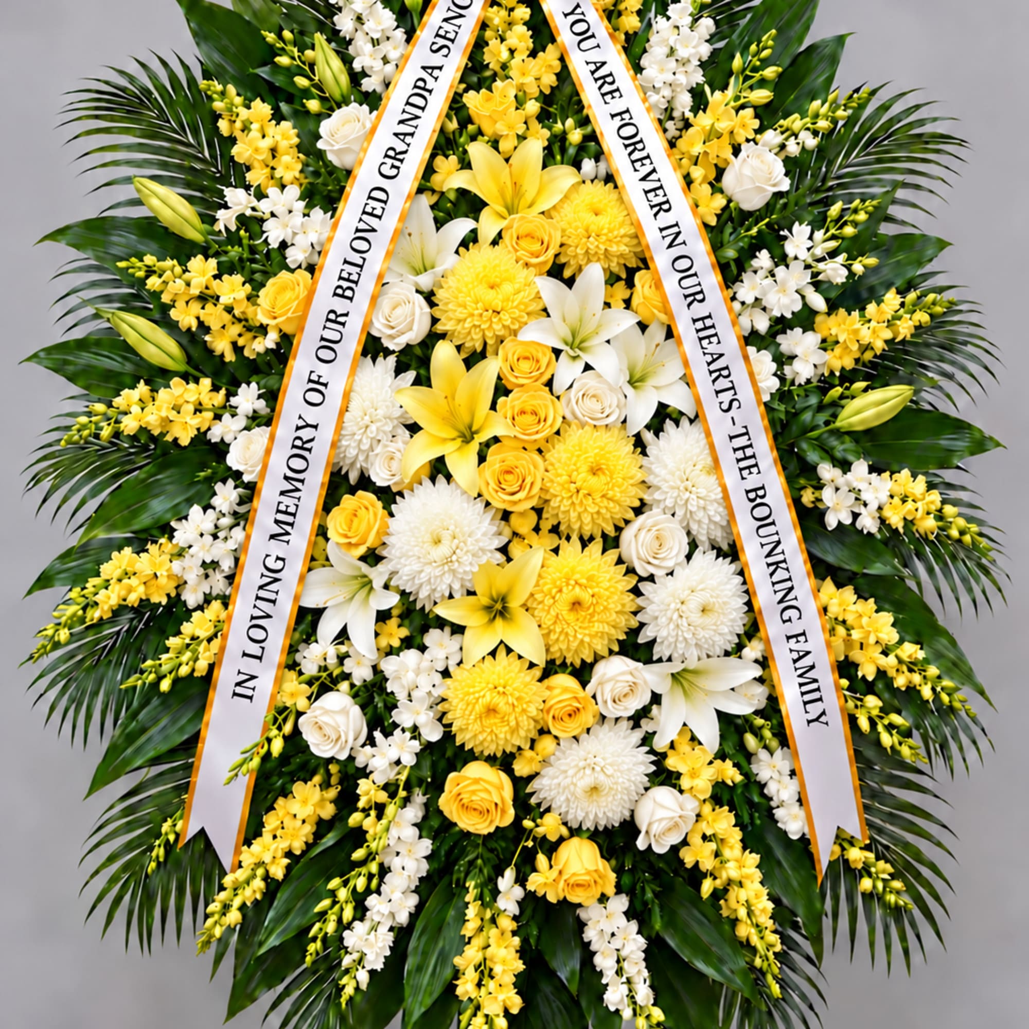Standing funeral wreath of yellow and white flowers with memorial ribbons