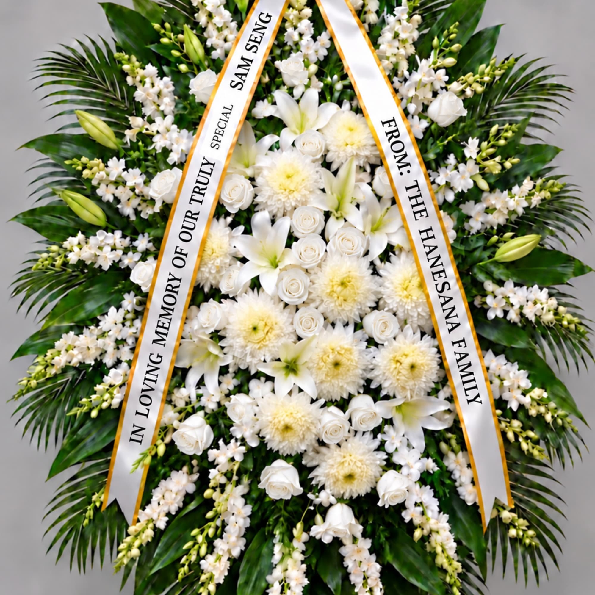 White funeral wreath with ribbon tribute and mixed blooms