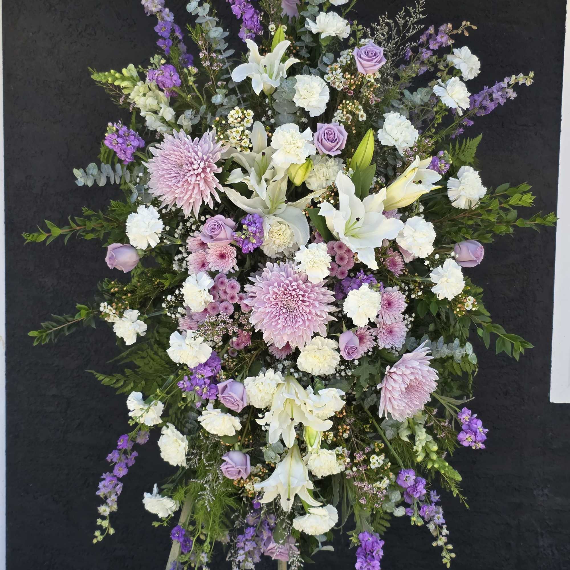 Dense pink lilies and clusters of red and blush roses create the