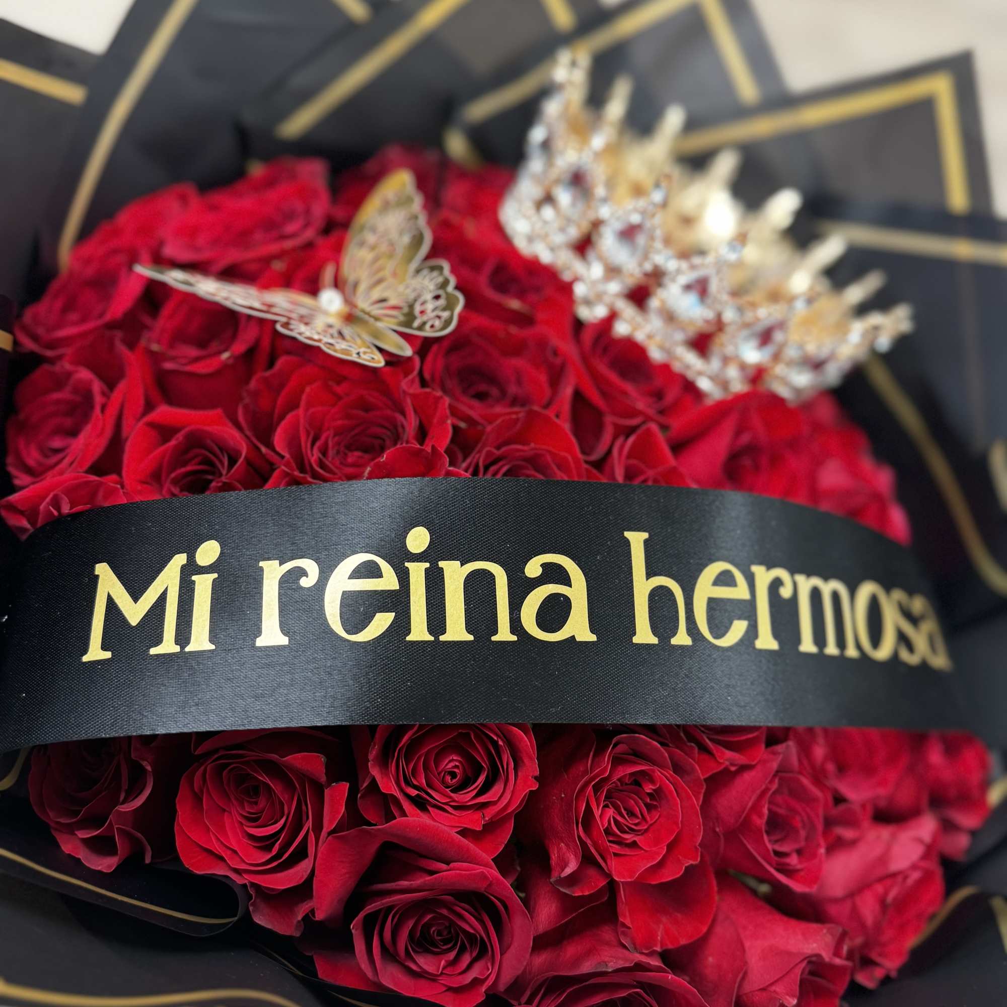 Red rose bouquet with a black ribbon and gold crown accents