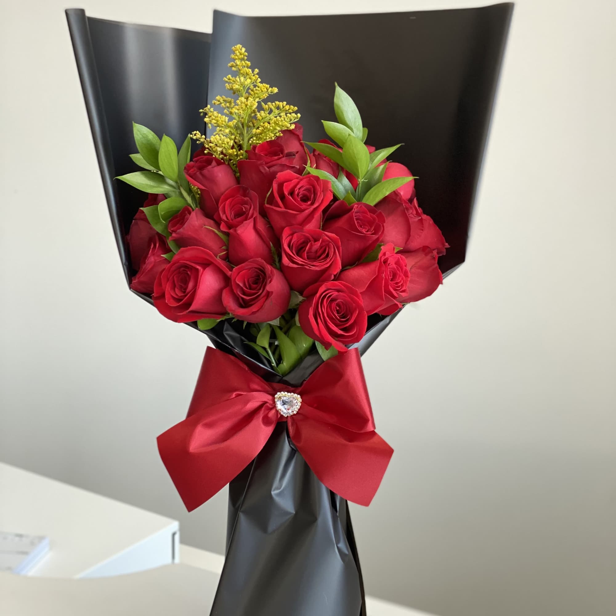 Bouquet of red roses wrapped in black paper with a red ribbon
