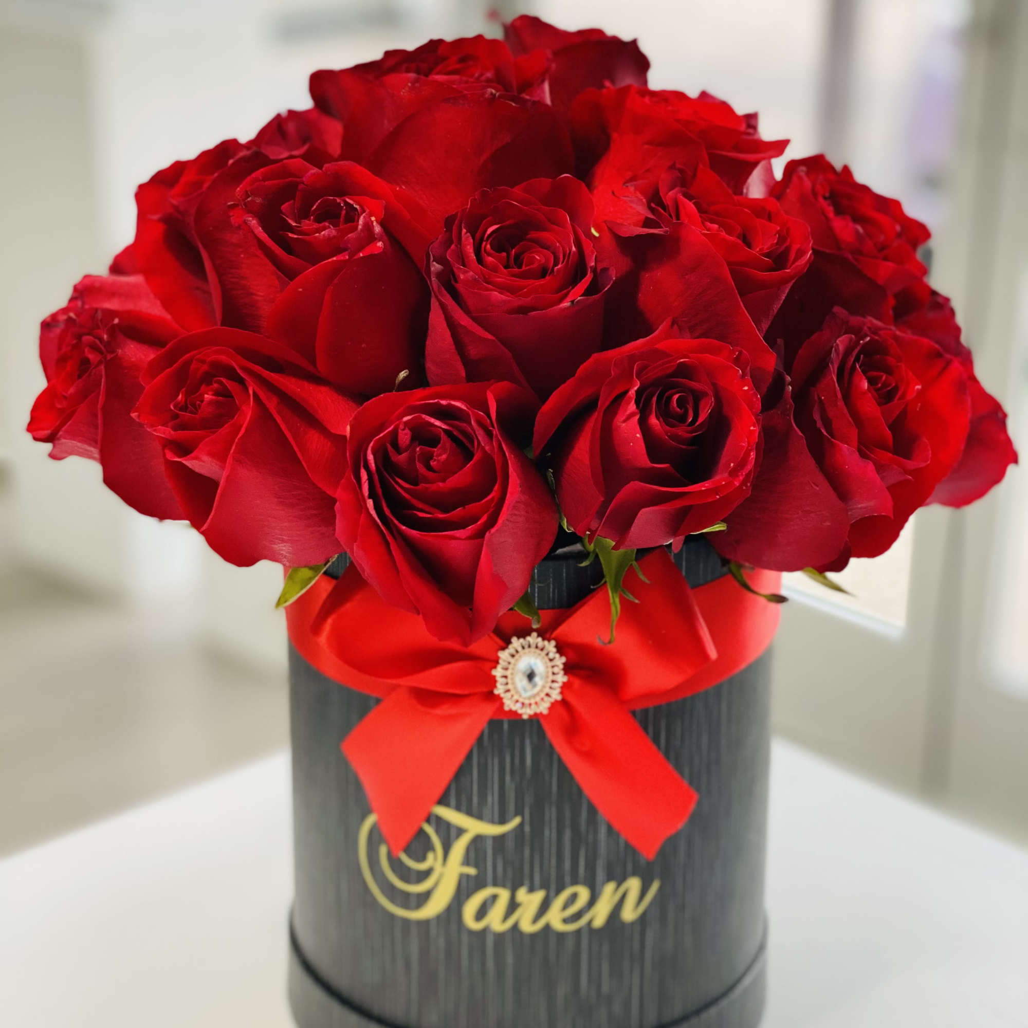 Red roses arranged in a black round box with a red ribbon