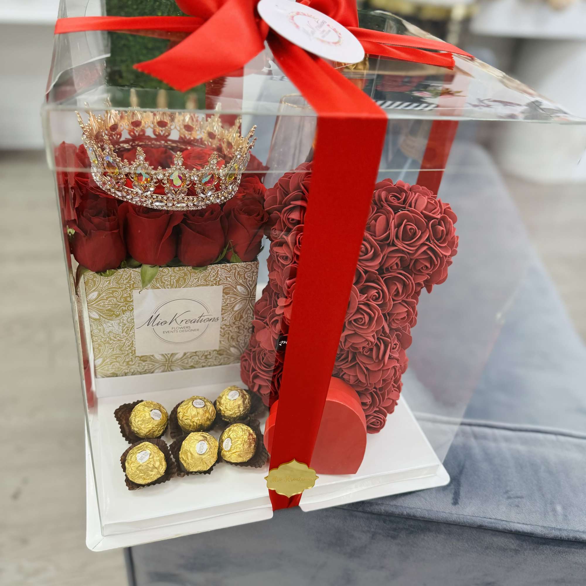 Gift box with red roses, a rose-shaped heart, and chocolates tied with a red ribbon
