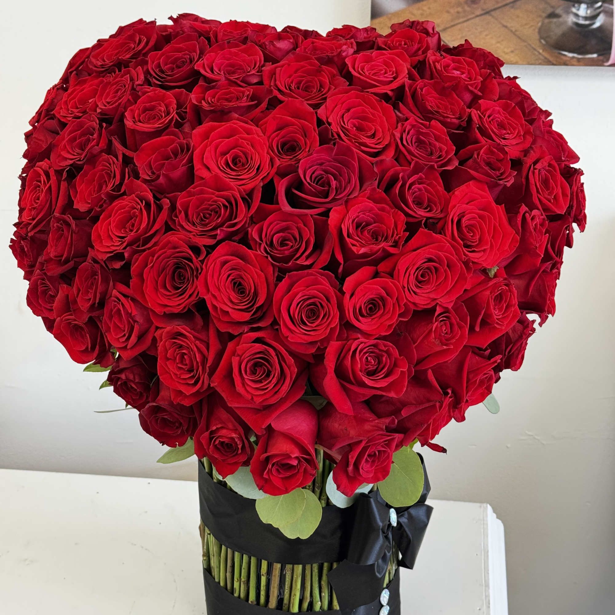 Large bouquet of red roses in a black wrapped vase