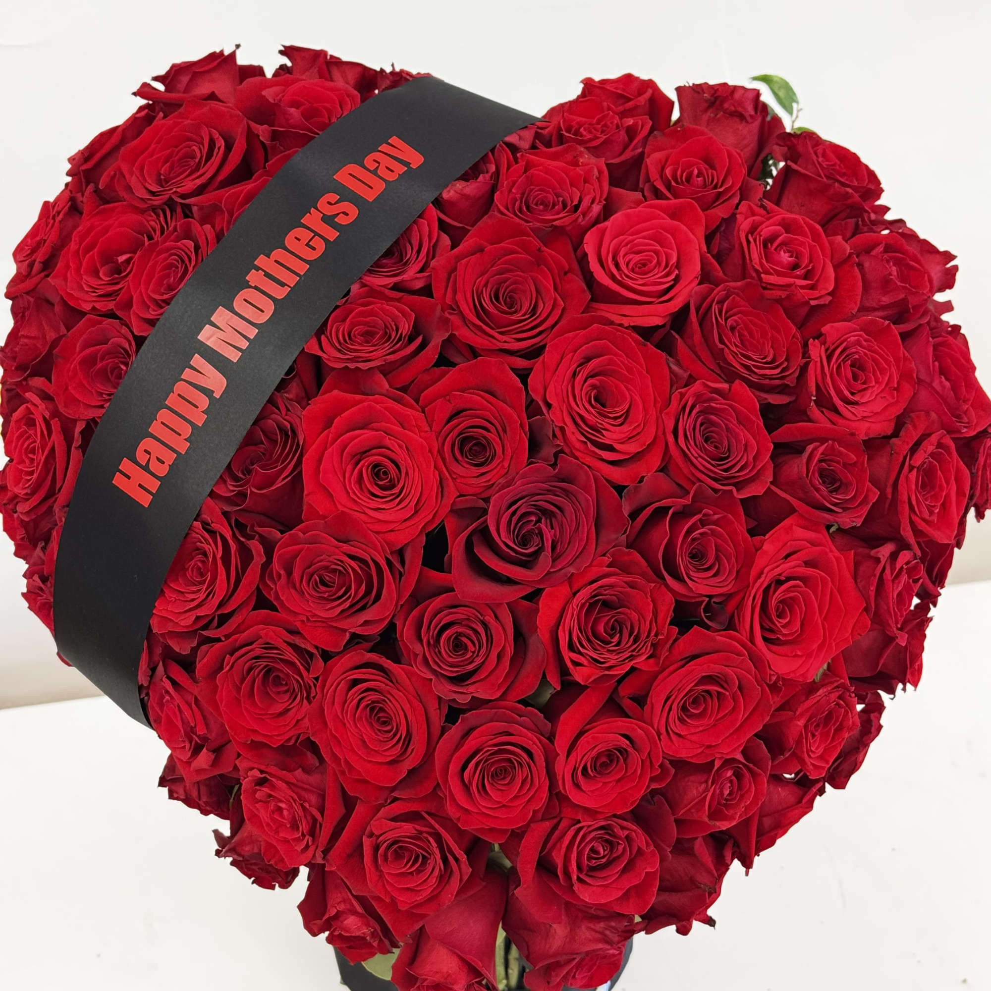 Heart-shaped bouquet of red roses with a Happy Mother's Day ribbon
