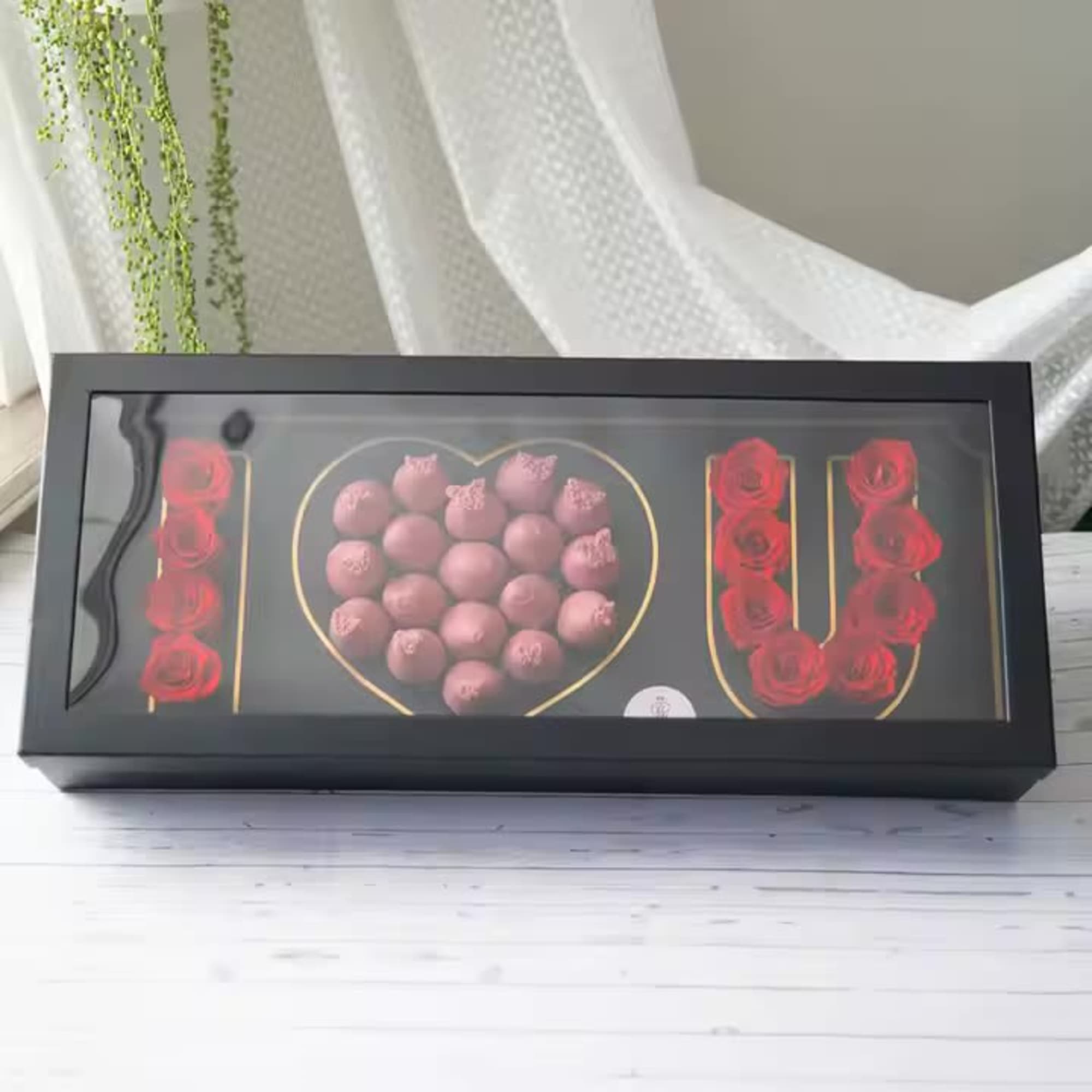 Black gift box with red roses and pink chocolates arranged as "I LOVE U"