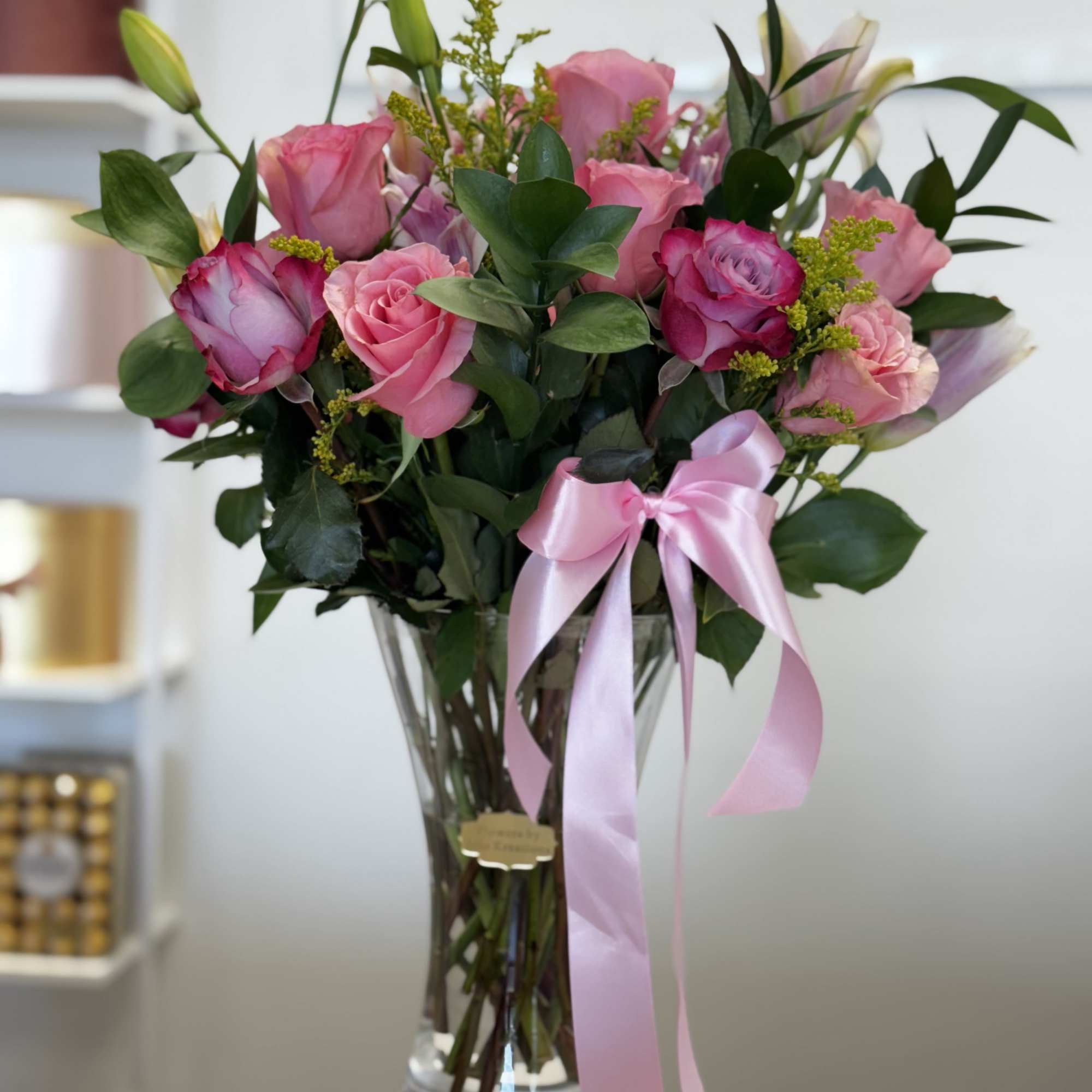 Pink roses in a clear glass vase with a pink ribbon
