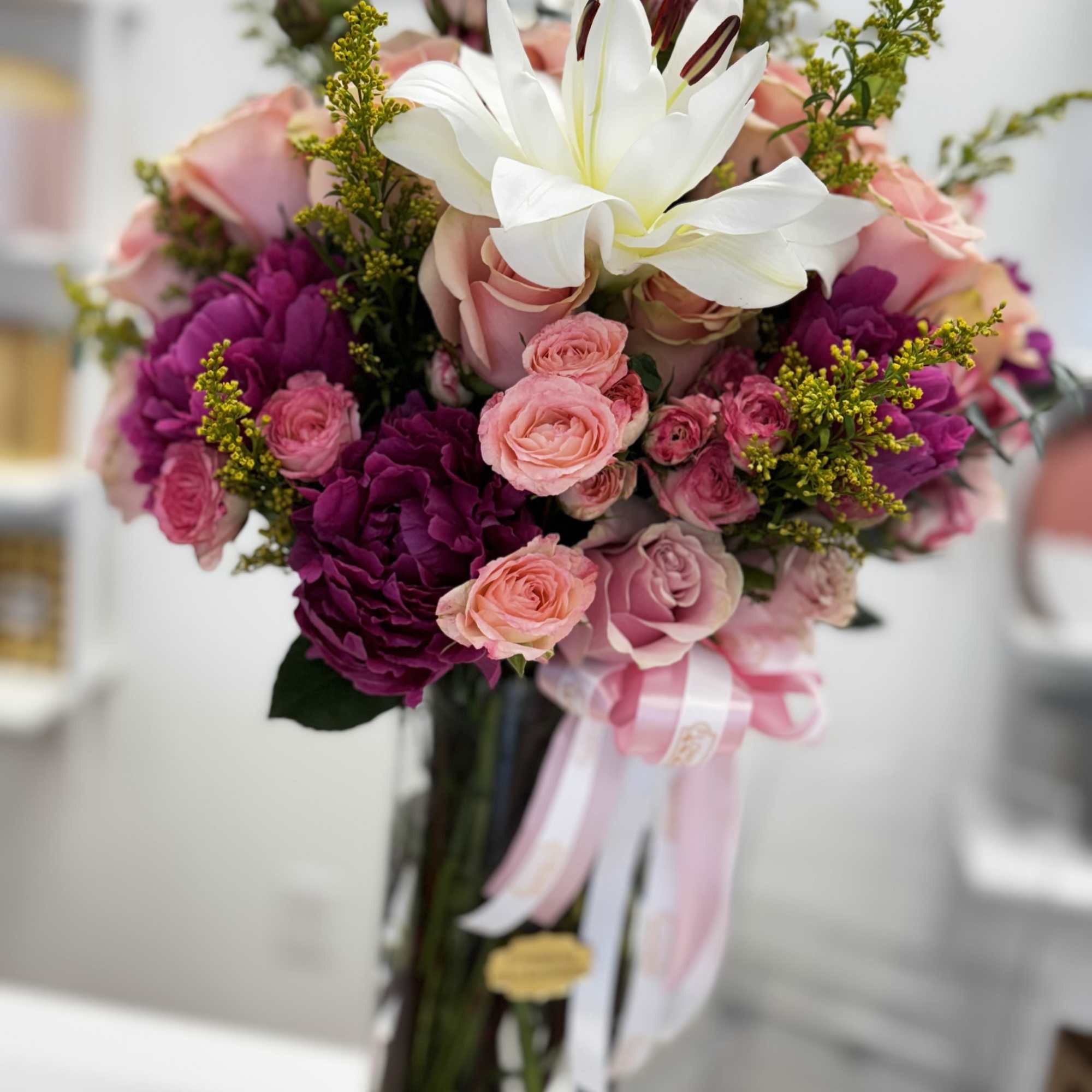 Bouquet of pink and purple roses with a white lily in a glass vase