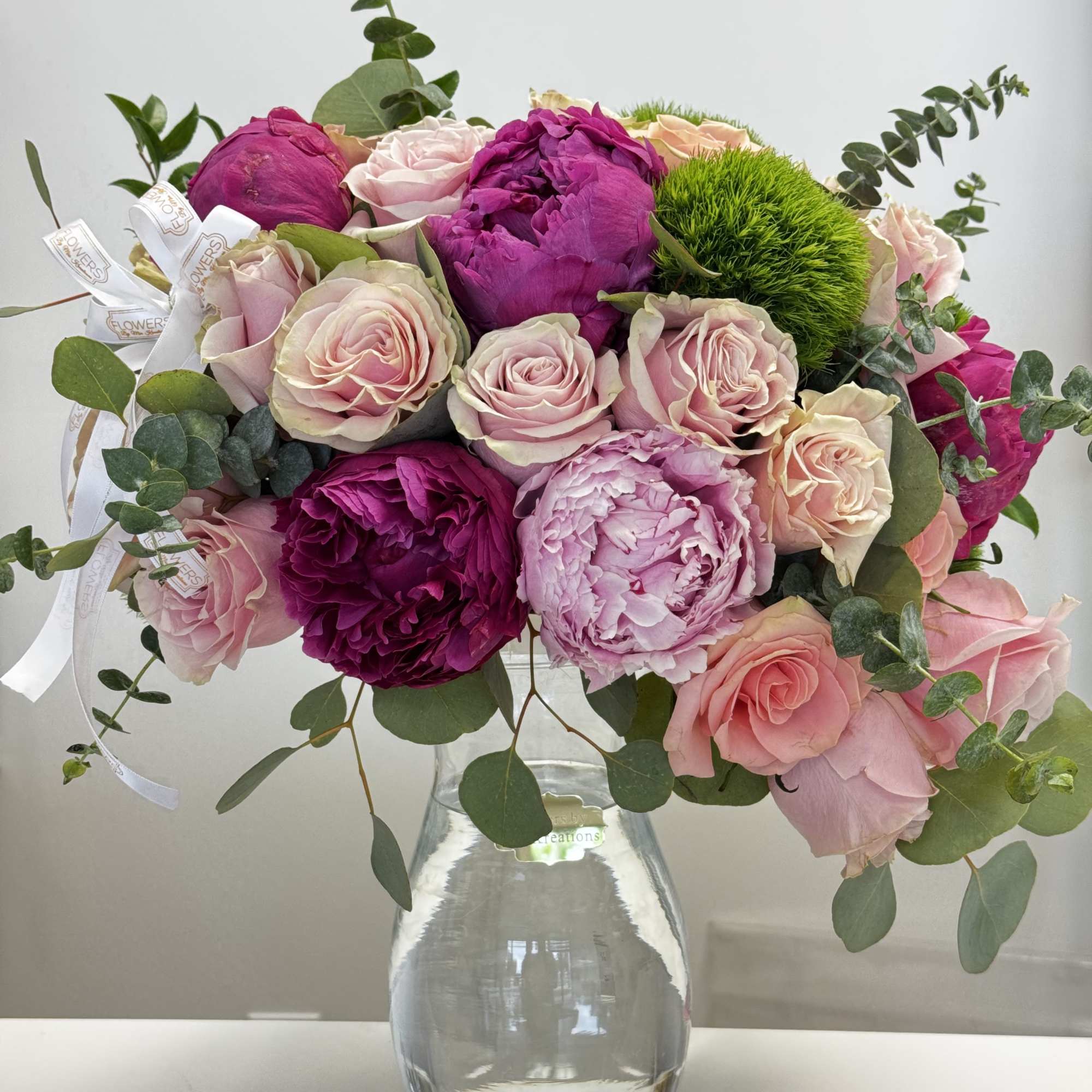 Pink and magenta roses and peonies in a clear glass vase