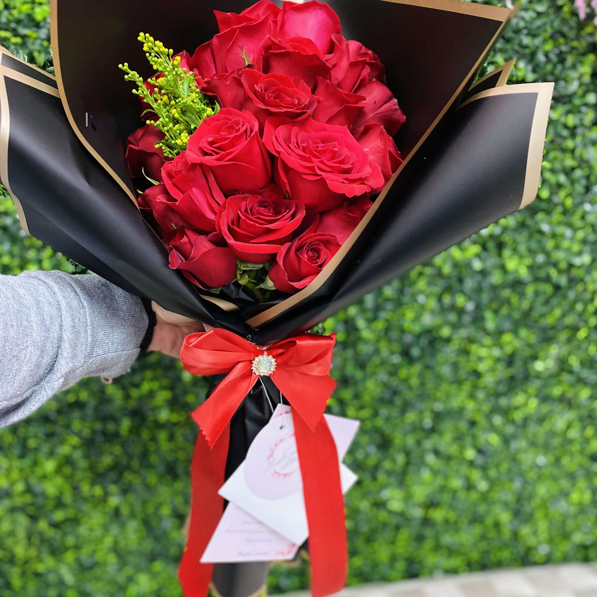 Bouquet of red roses wrapped in black paper with a red ribbon