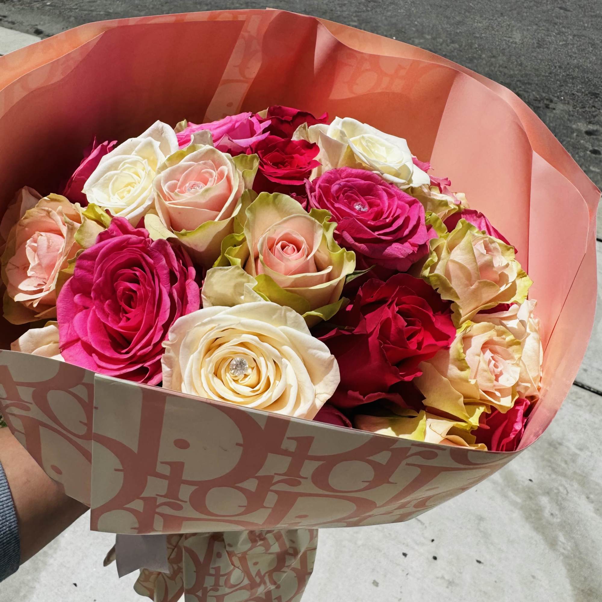 Bouquet of pink, red, and white roses wrapped in peach paper