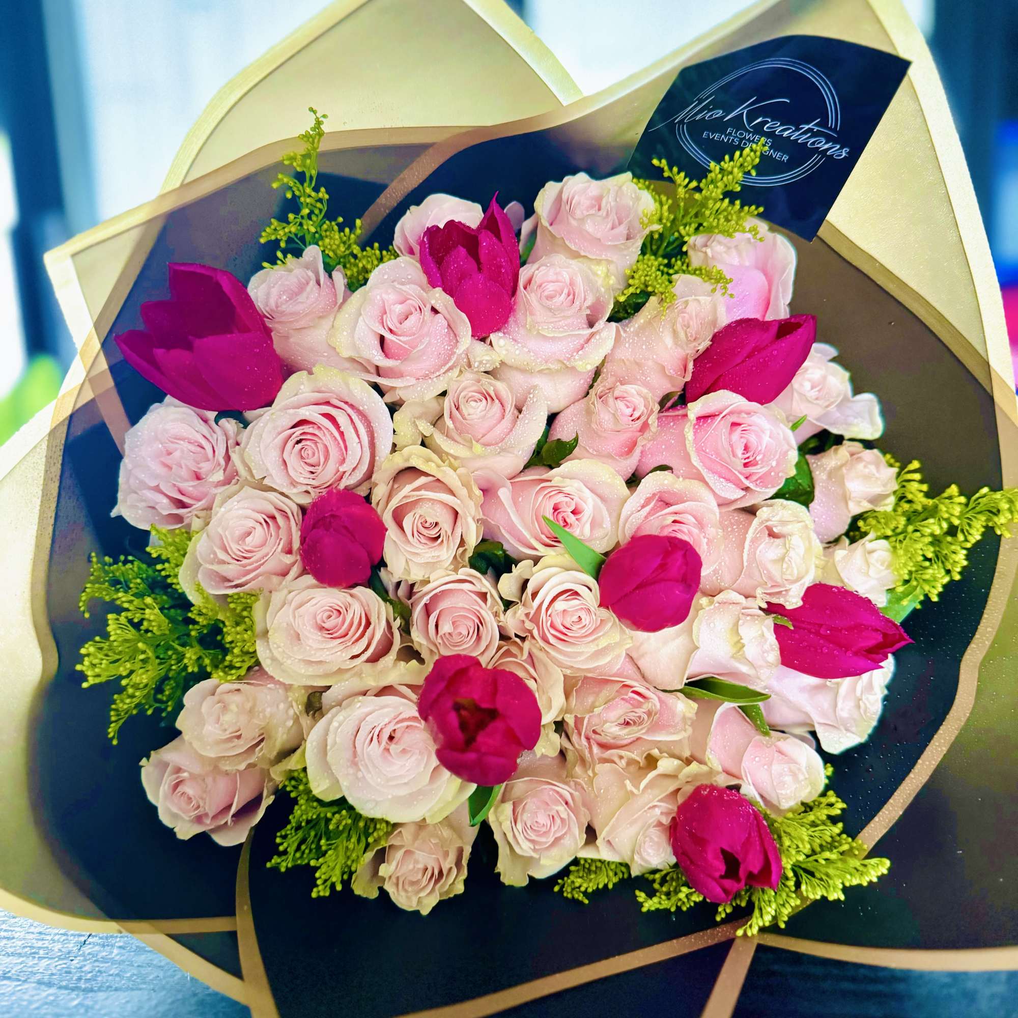 Bouquet of pale pink and hot pink roses wrapped in dark paper