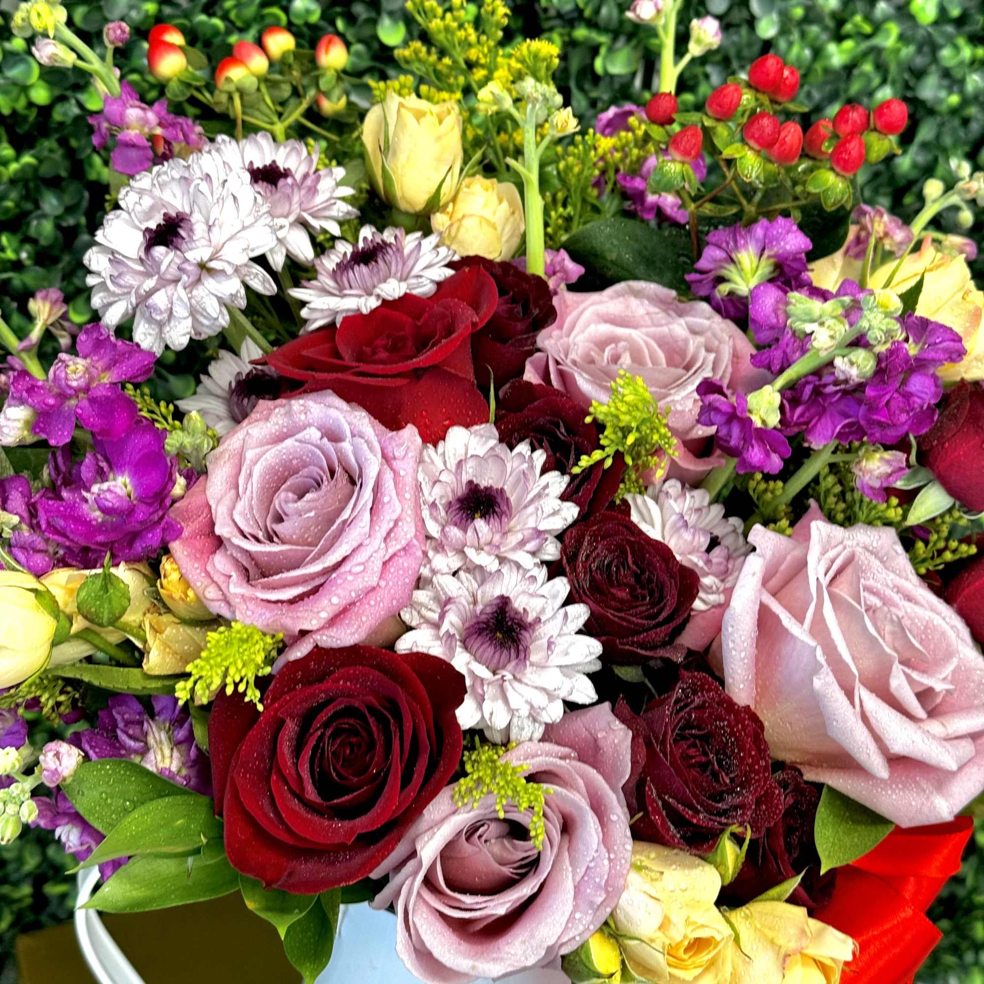Mixed bouquet of roses and daisies in a white container