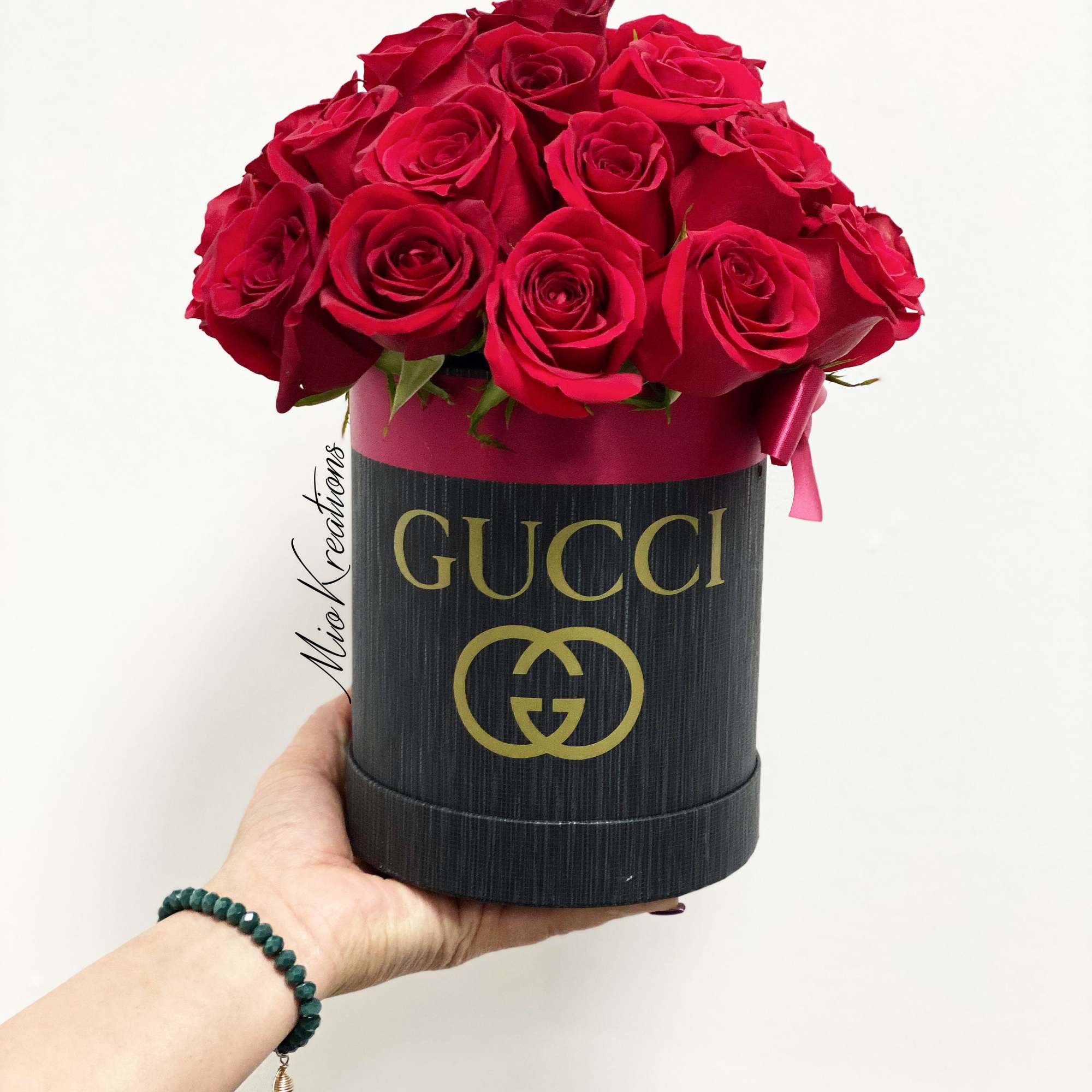 Red roses arranged in a black Gucci hat box