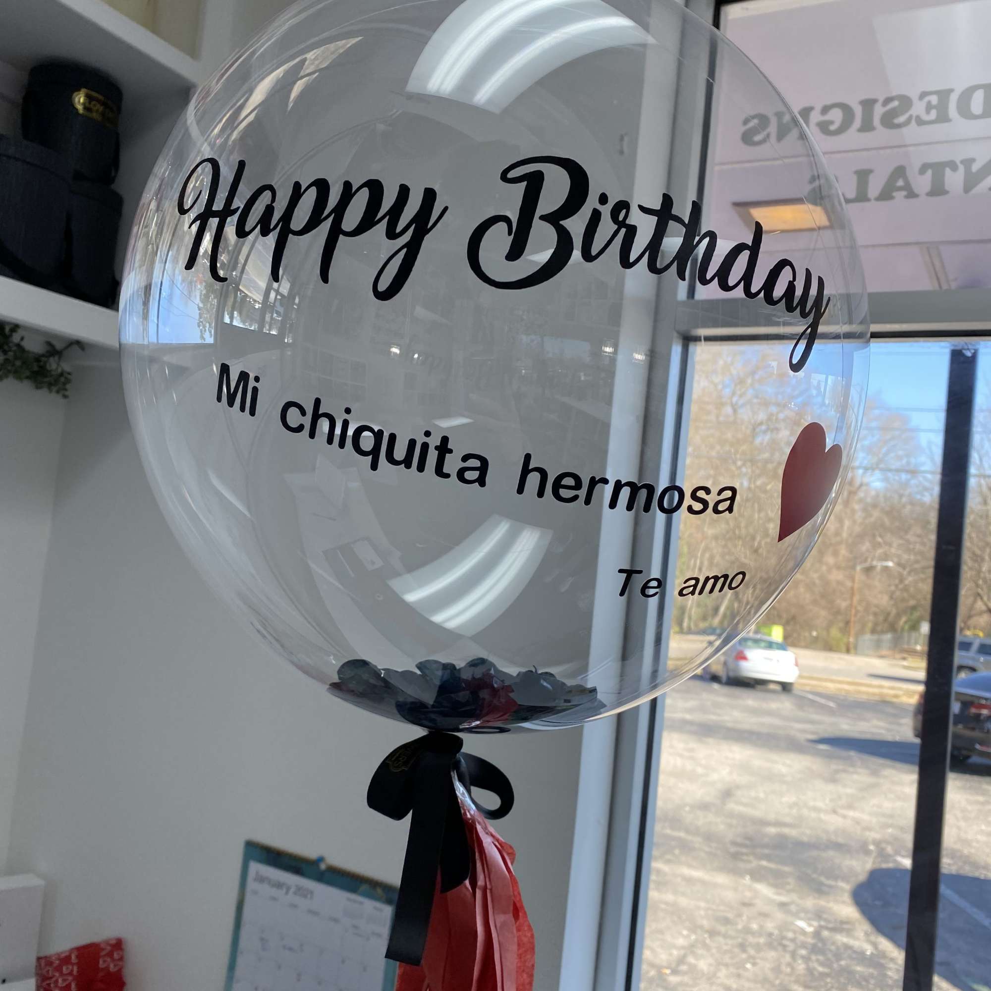 Clear birthday balloon with black text and red tassels