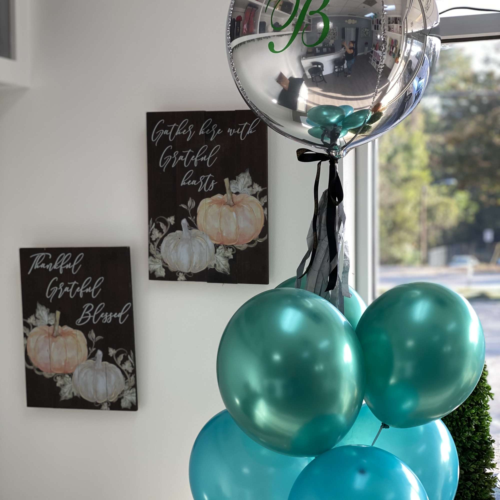 Cluster of teal and silver balloons with ribbon indoors