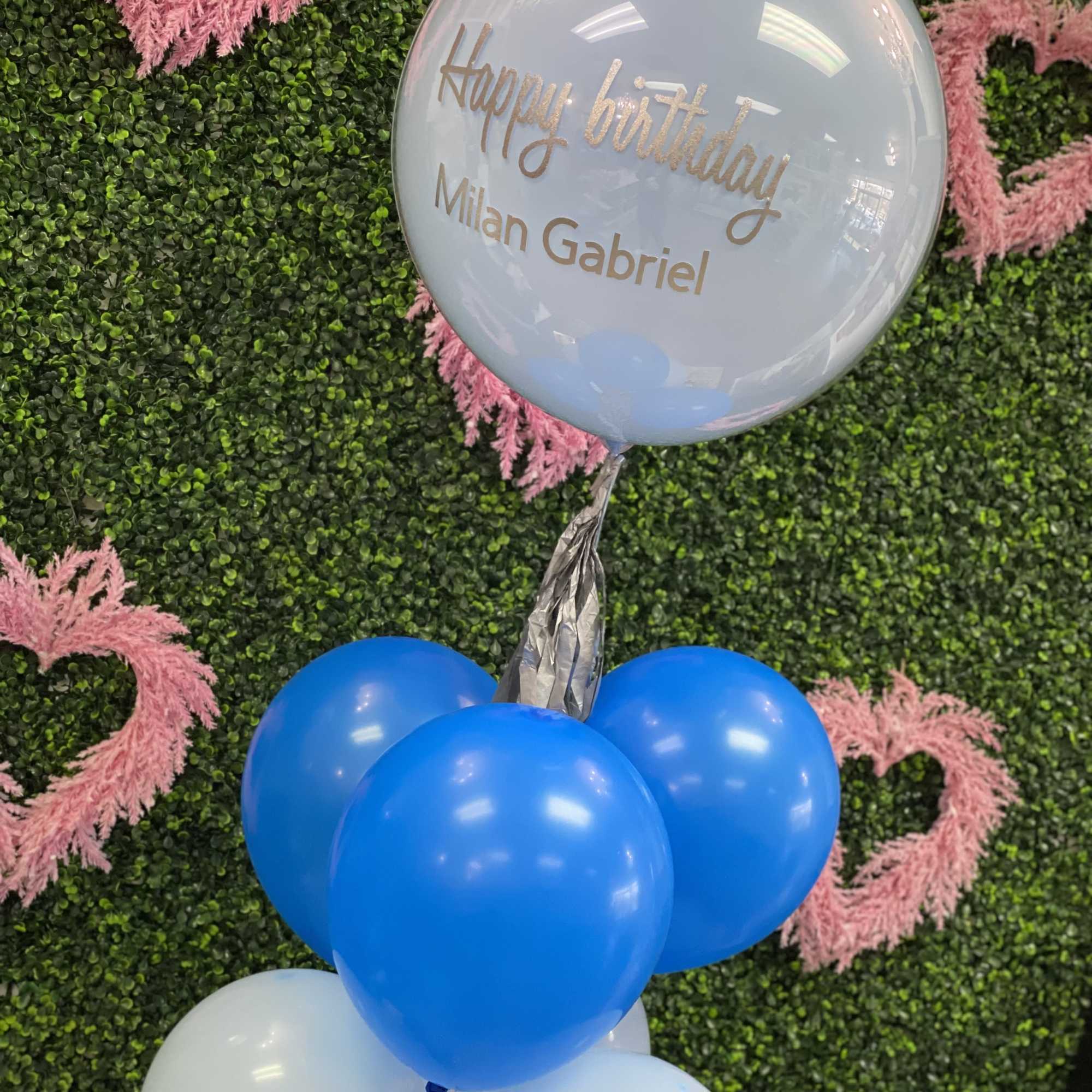 Birthday balloon cluster with a personalized clear balloon and blue and white balloons