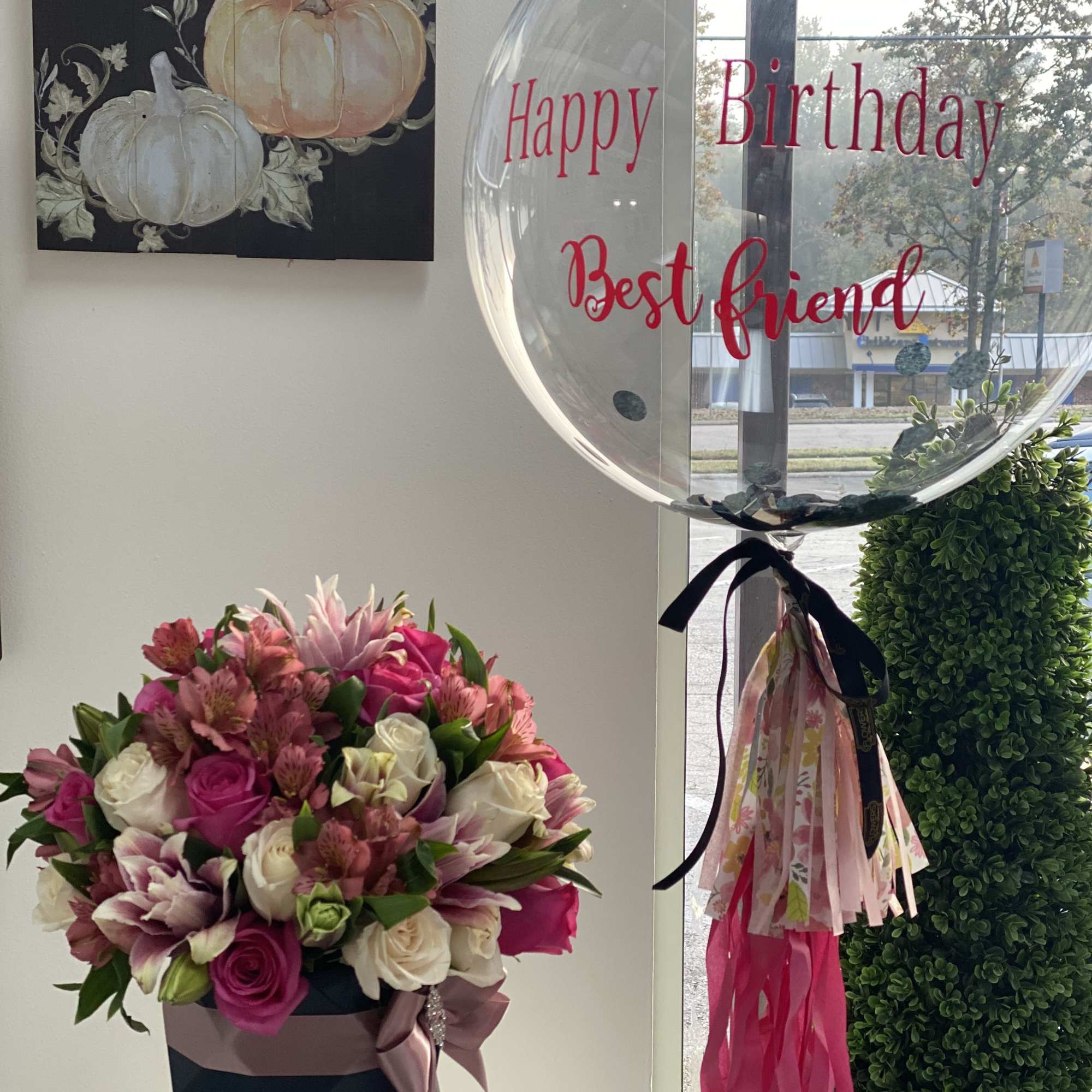 Pink and white rose bouquet in a black box beside a clear birthday balloon