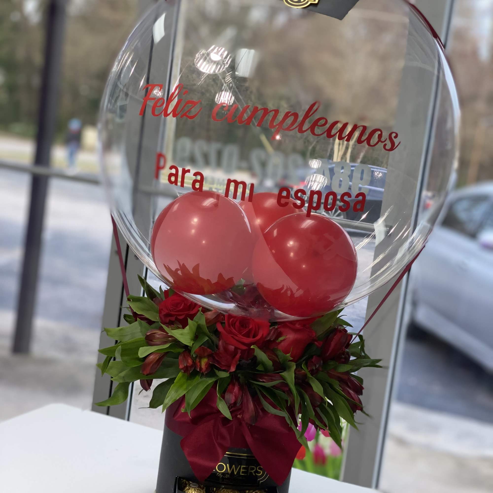 Red rose arrangement with balloons in a clear balloon box