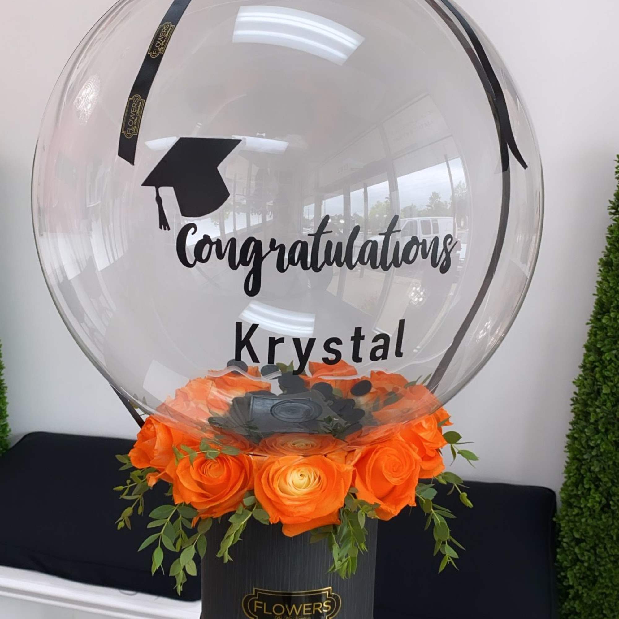 Clear balloon display with orange roses and a congratulations message