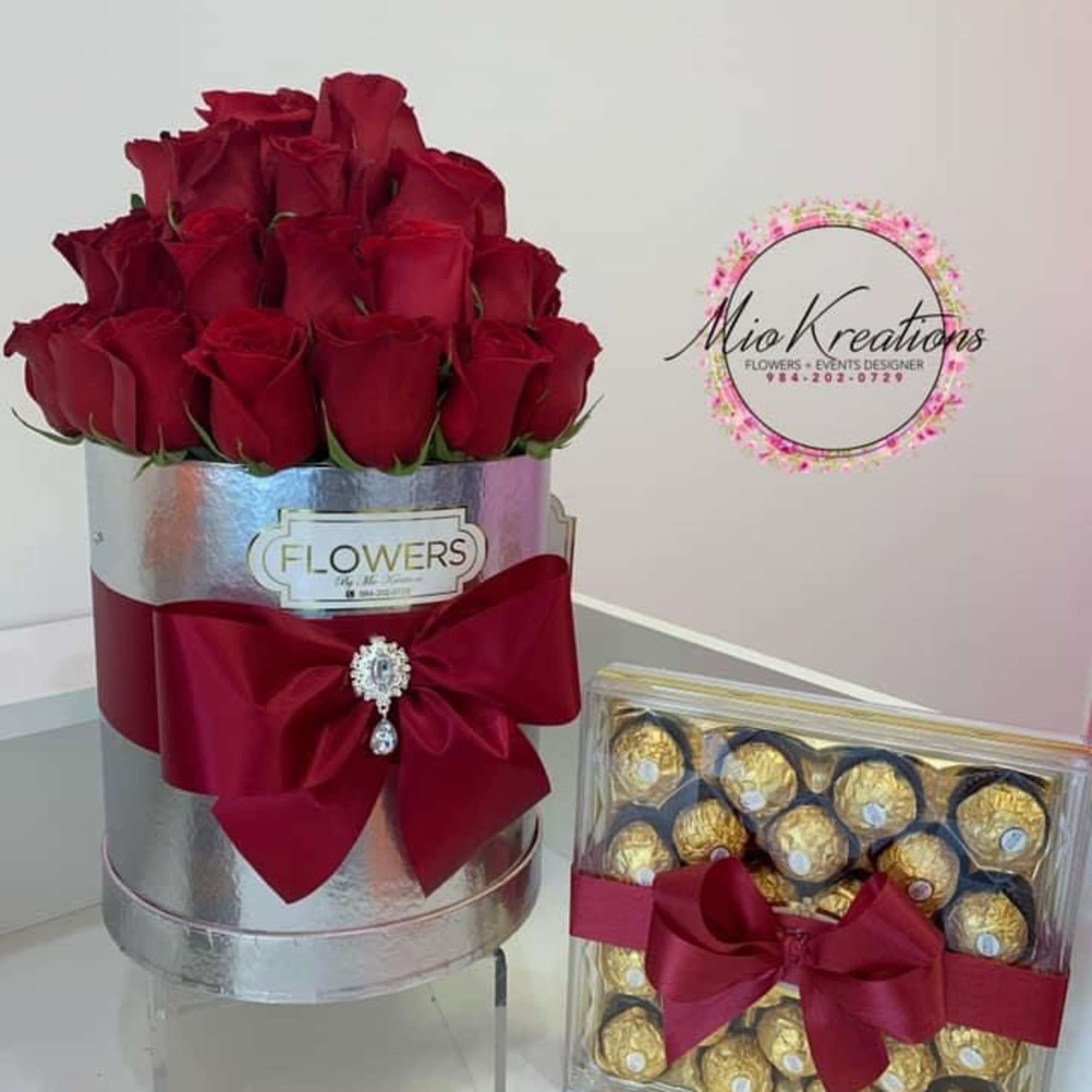 Red roses in a silver hatbox beside a box of chocolates