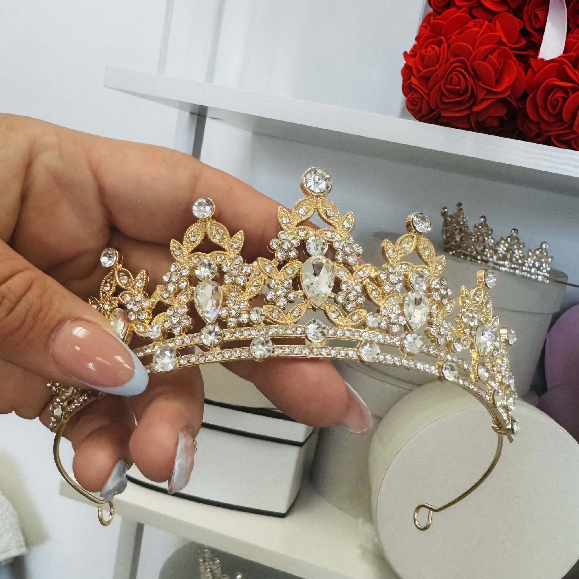 Hand holding a gold rhinestone tiara with clear crystals
