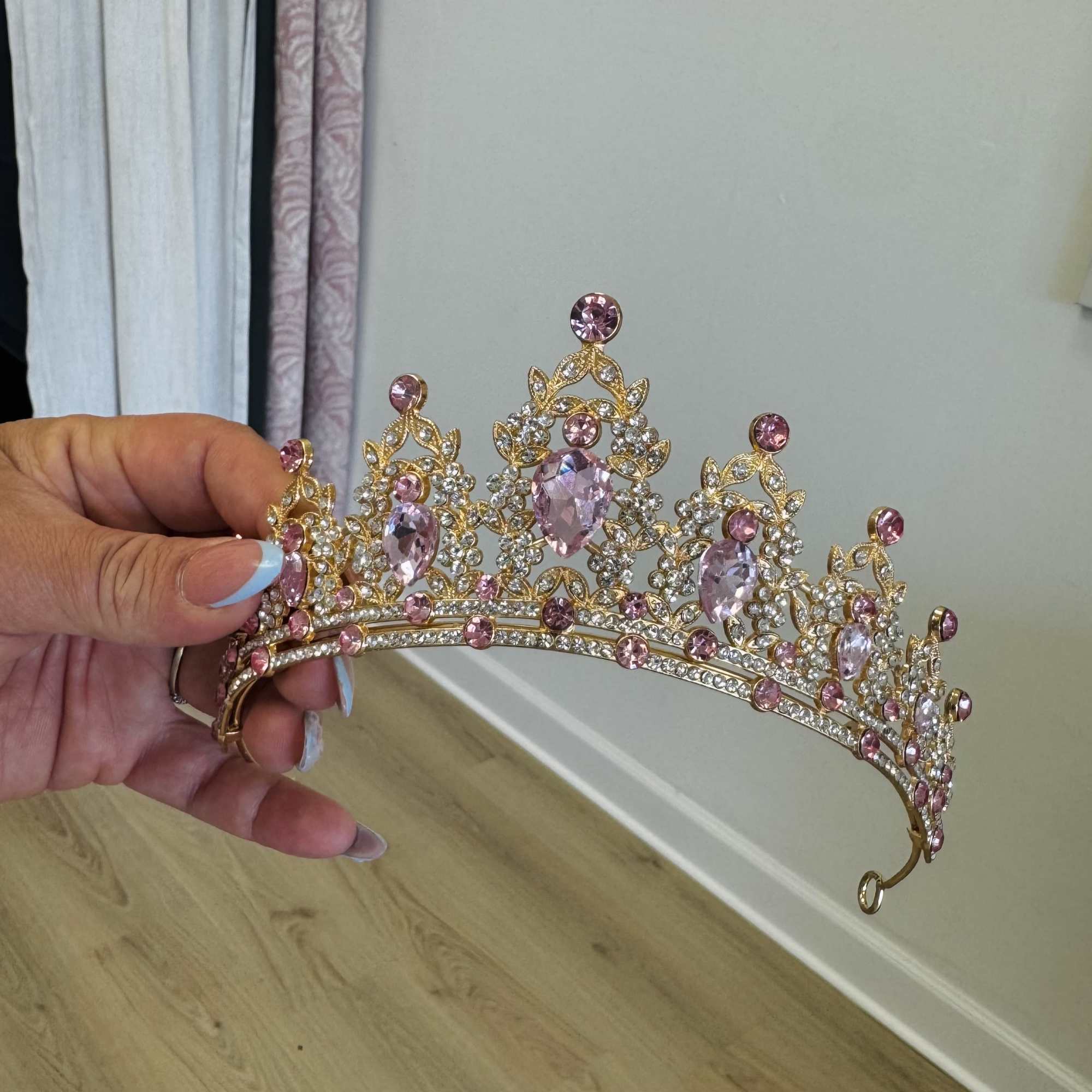 Hand holding a jeweled pink tiara