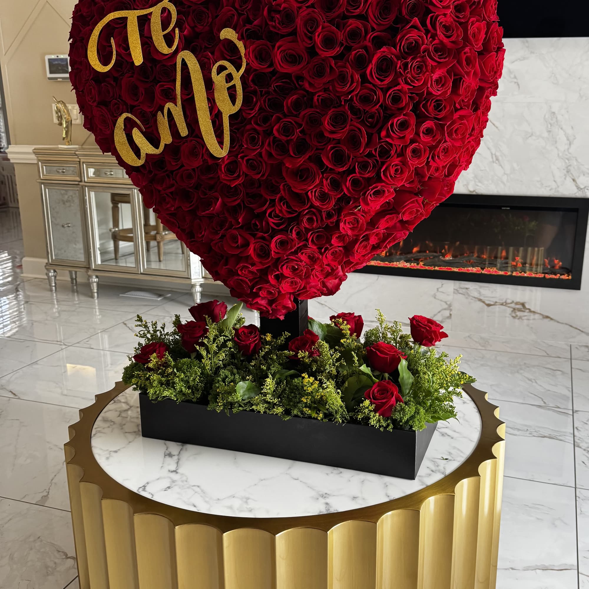 Heart-shaped red rose arrangement with gold lettering on a pedestal