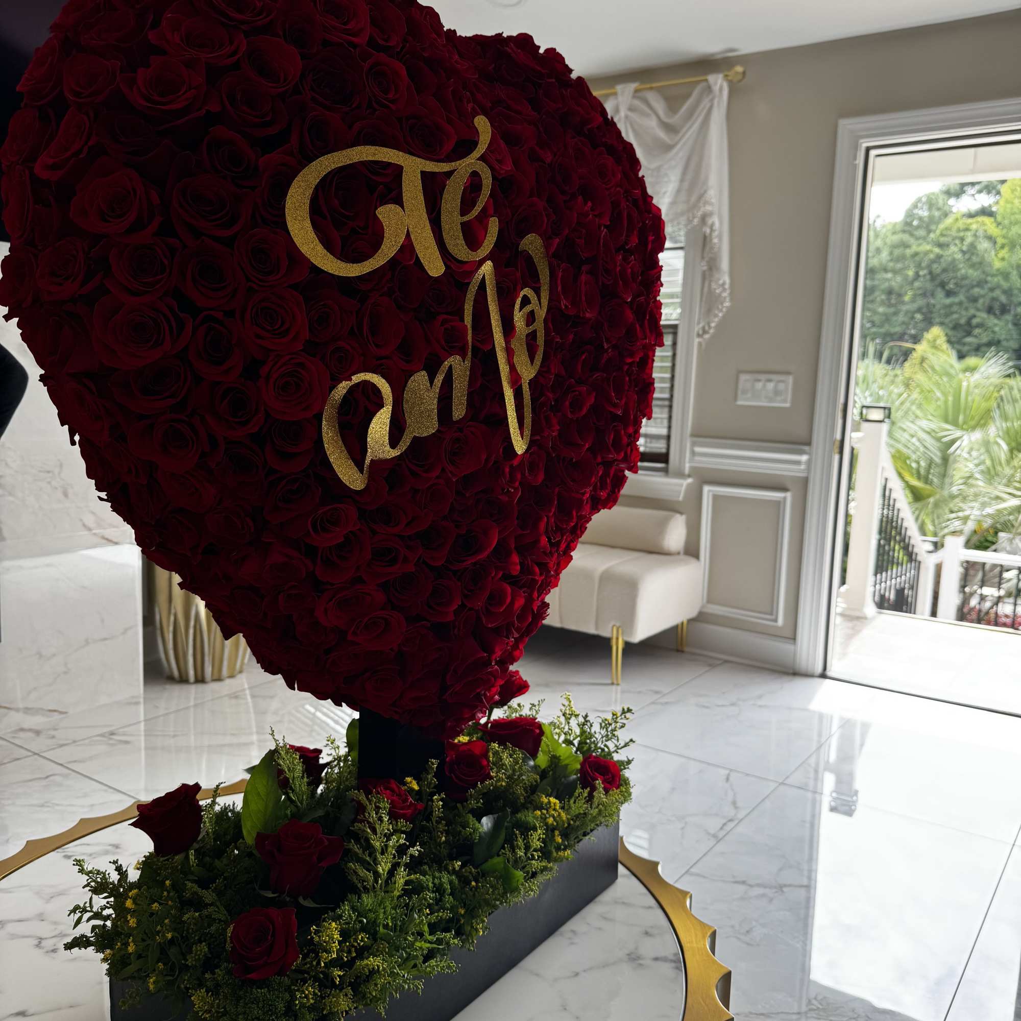 Heart-shaped red rose arrangement with gold lettering on a black base