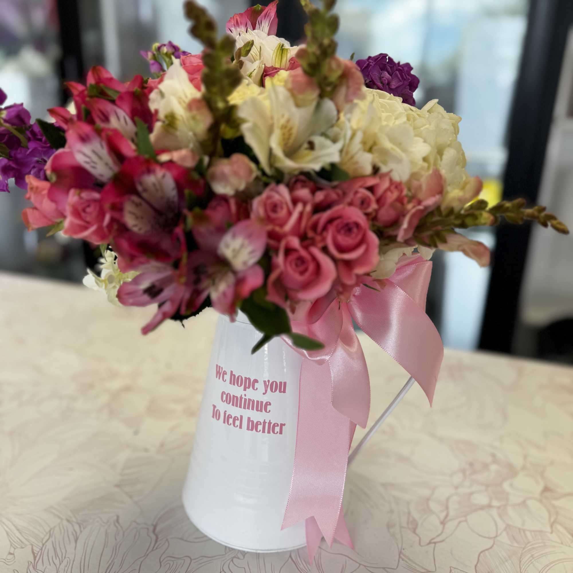 Pink and white mixed bouquet in a white container with a pink ribbon