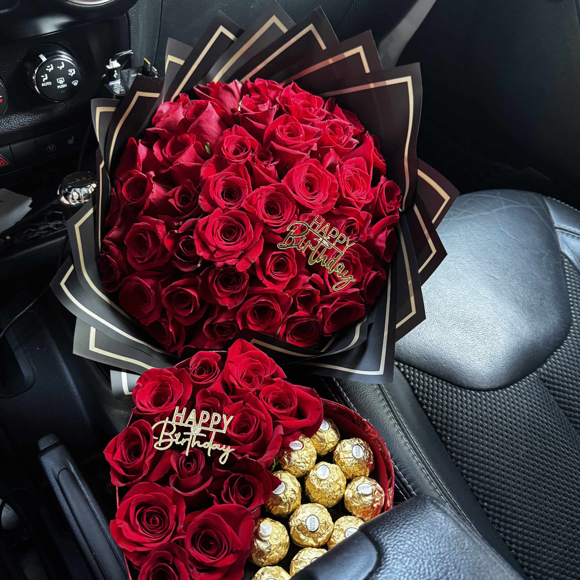Two red rose gift arrangements with chocolate candies in a car interior