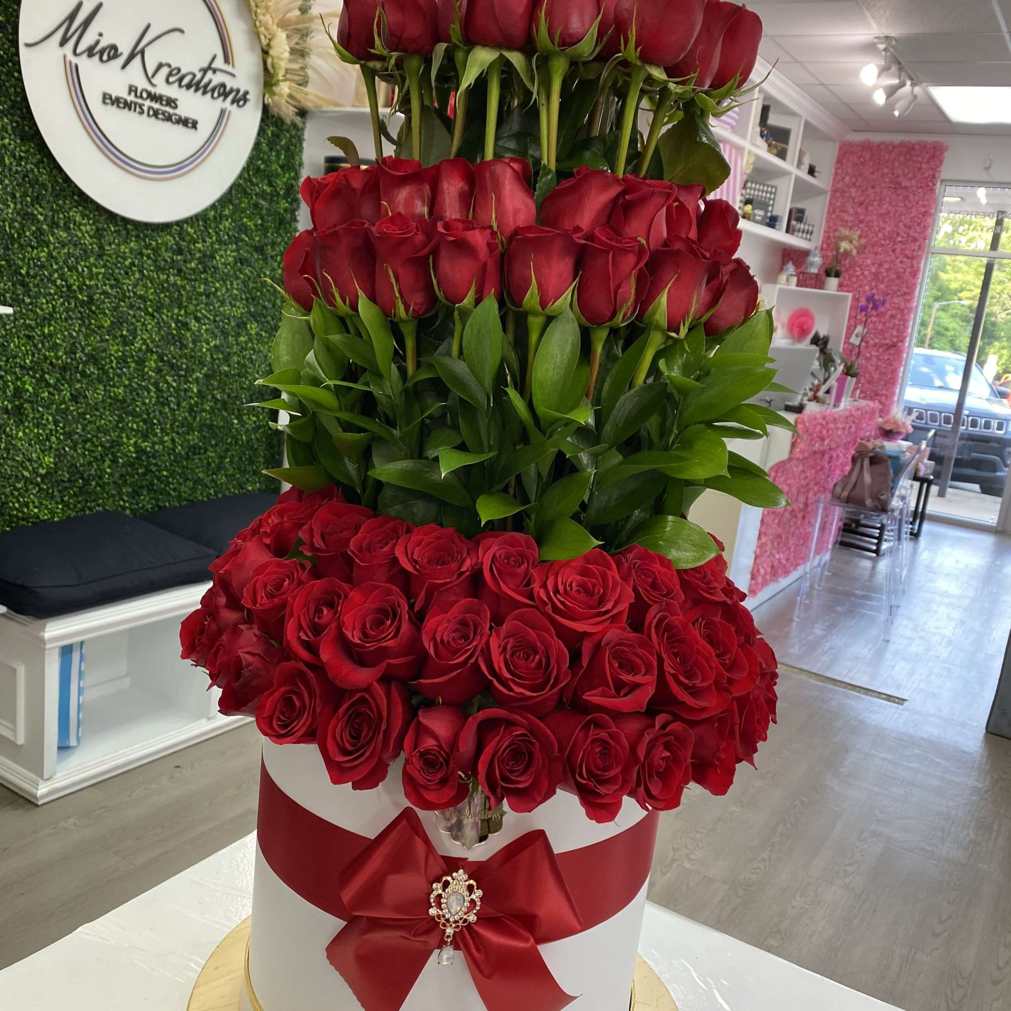 Tall tower of red roses in a white hatbox with a red bow