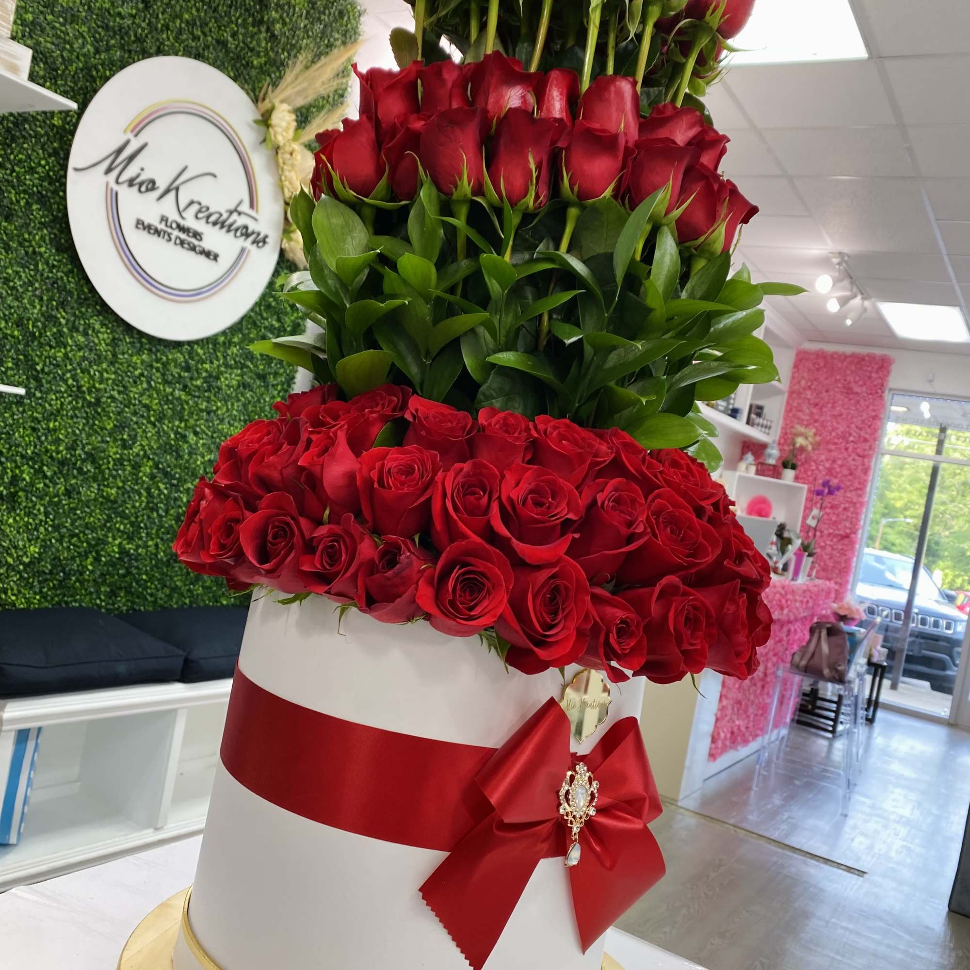 Tiered arrangement of red roses in a white hatbox with a red ribbon