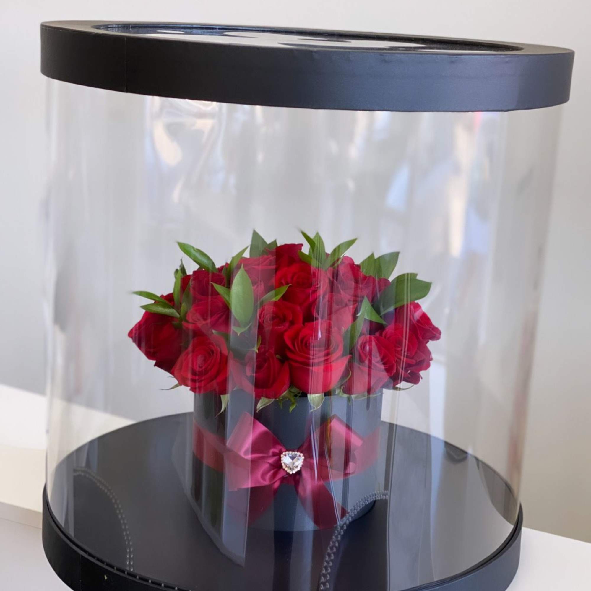 Red roses in a black hatbox with a clear dome cover